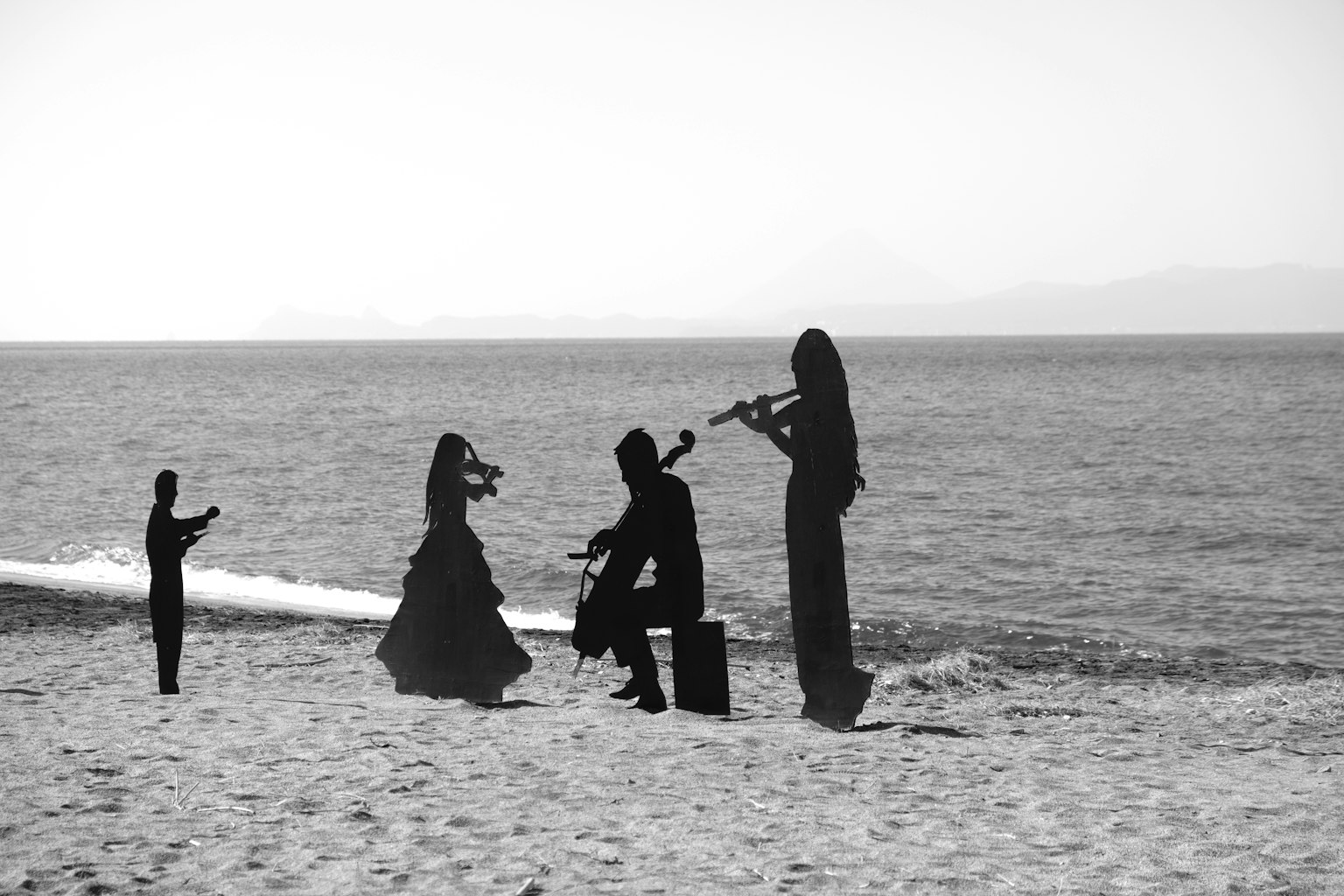 Silhouettes of people playing instruments on the beach
