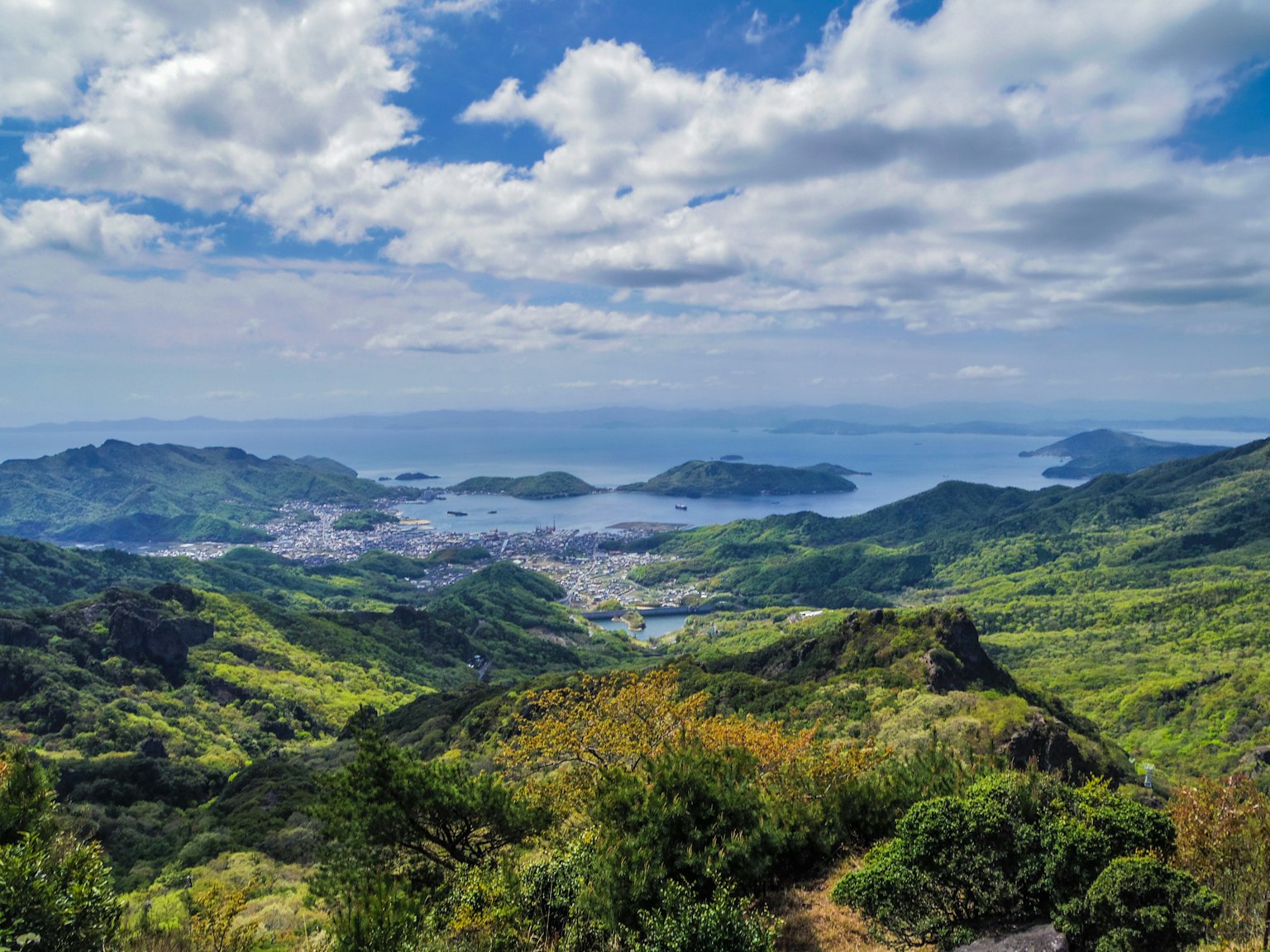 郁郁蔥蔥的綠色山脈俯瞰藍色海洋和明亮的天空