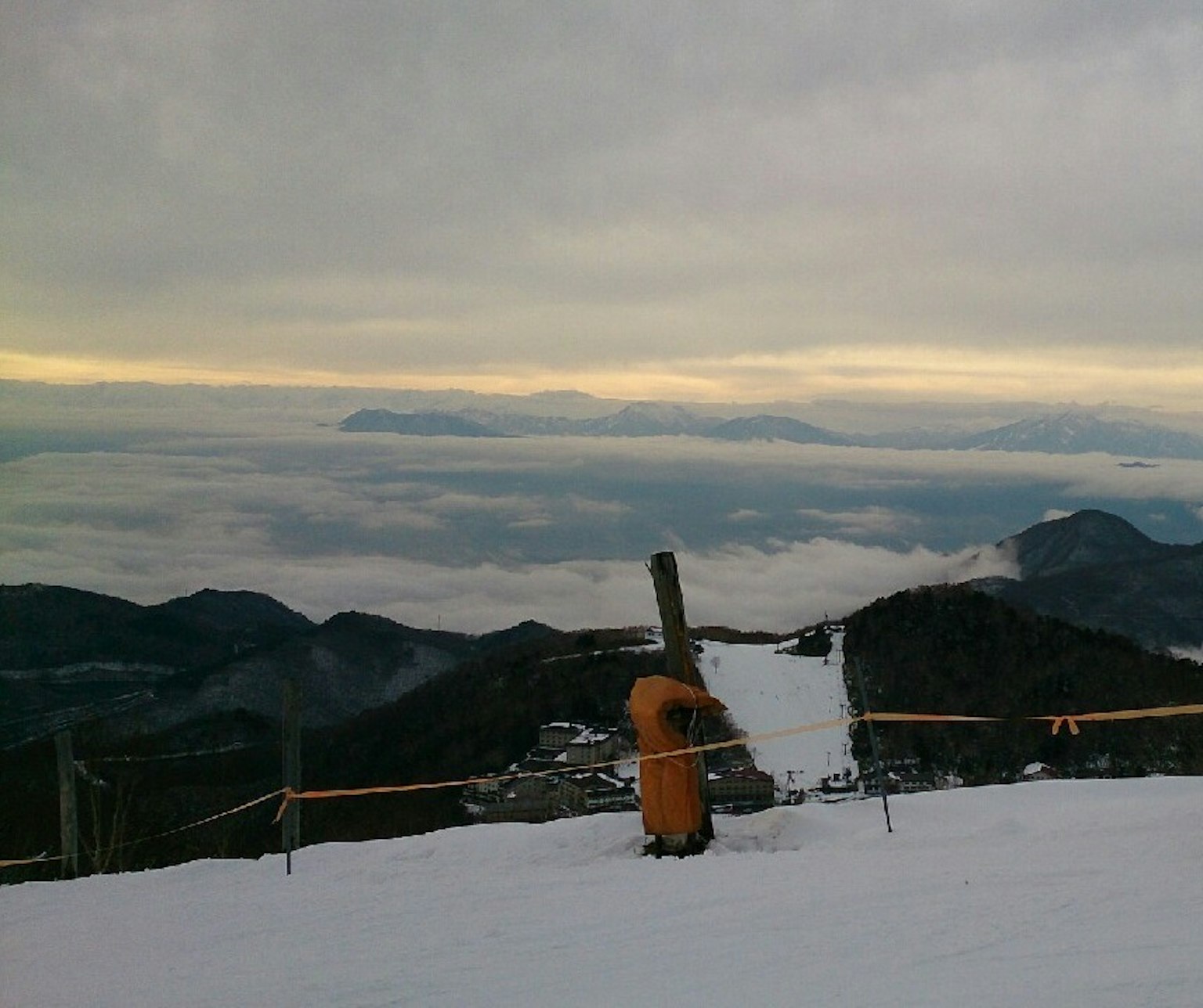 Pemandangan indah dari puncak gunung bersalju dengan awan rendah dan gunung jauh