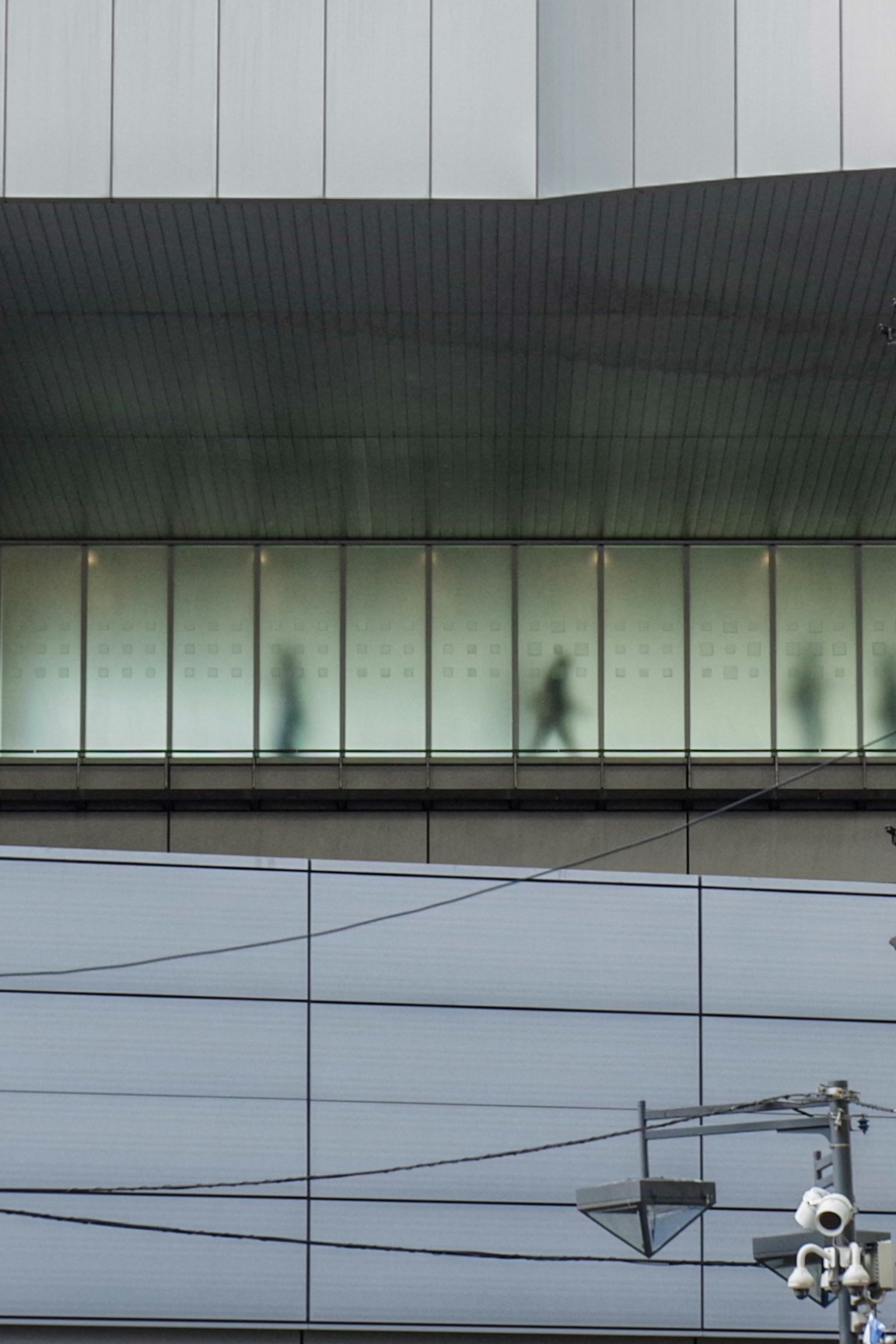 Silhouetten von Menschen, die gegen eine Glaswand eines modernen Gebäudes gehen