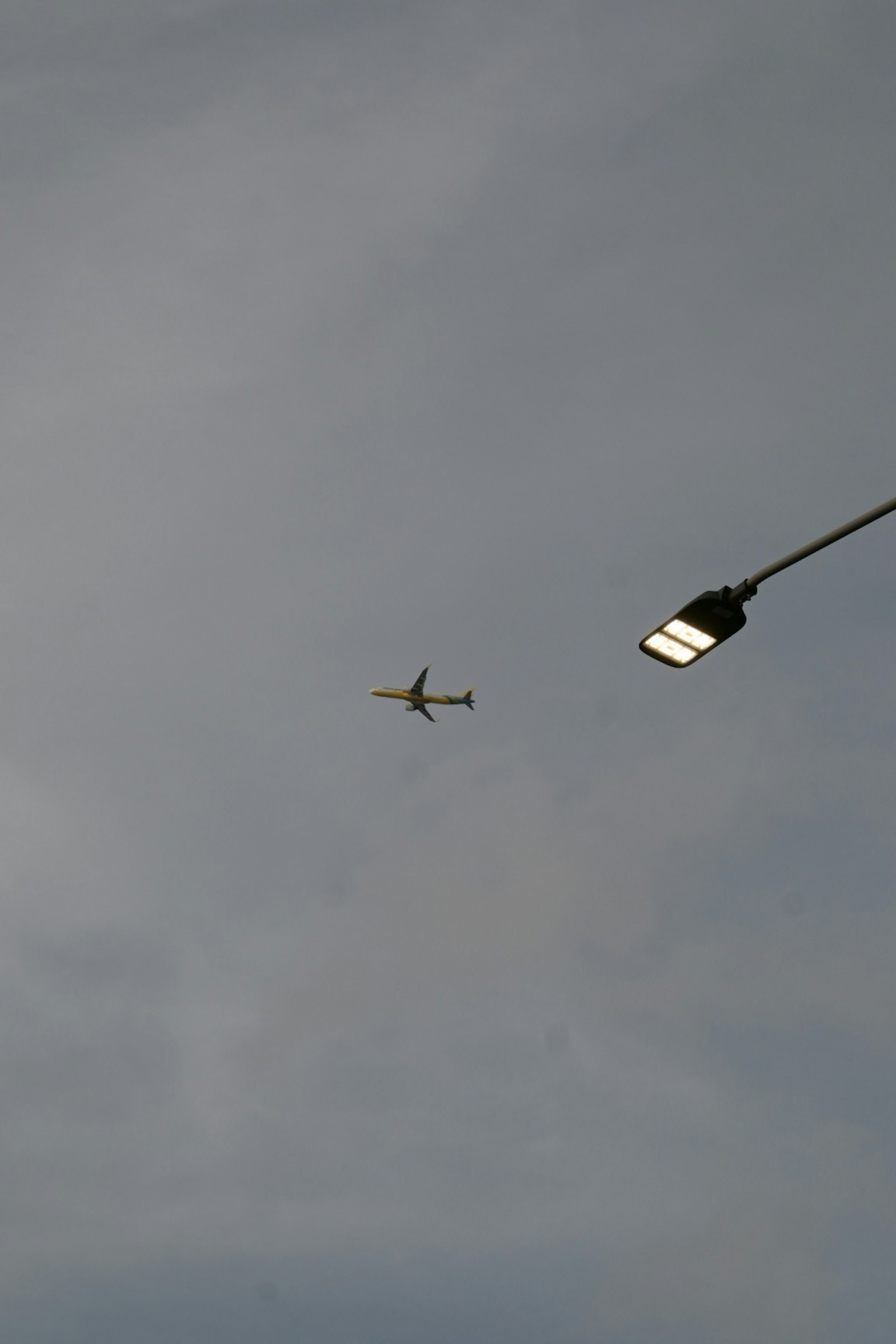 Un aereo che vola nel cielo vicino a un lampione