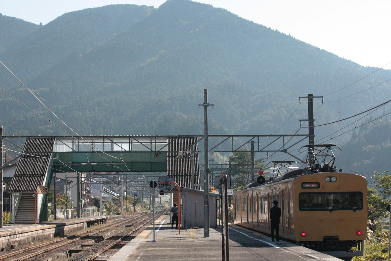 Kereta kuning di stasiun dengan latar belakang gunung