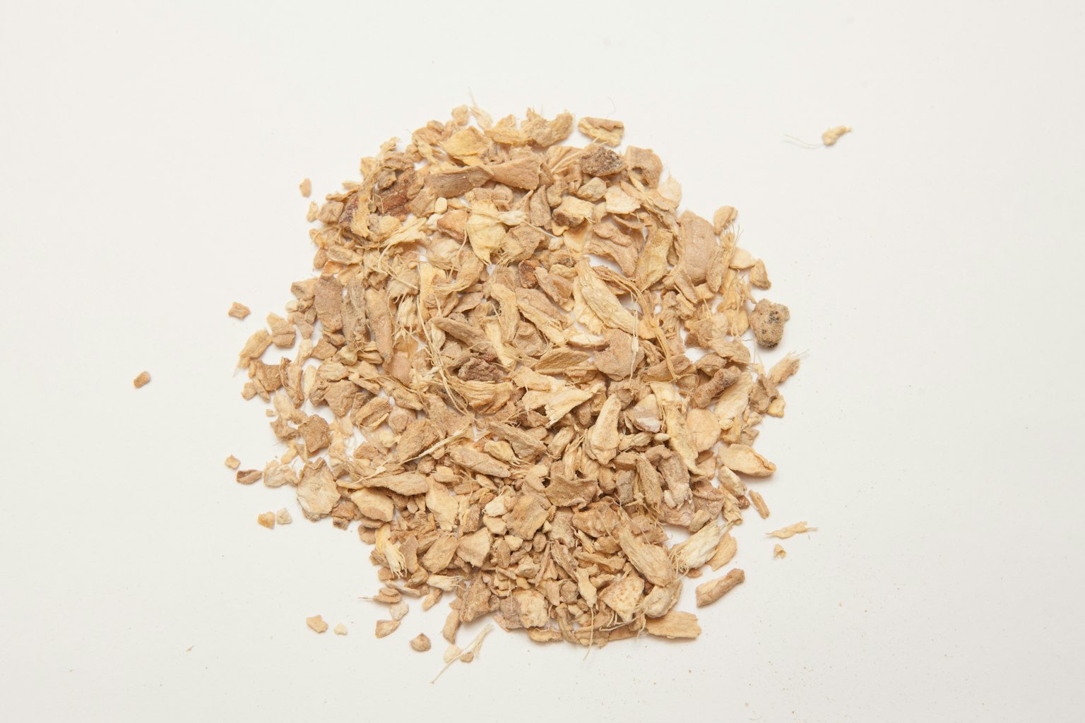 Dried ginger flakes piled on a white background