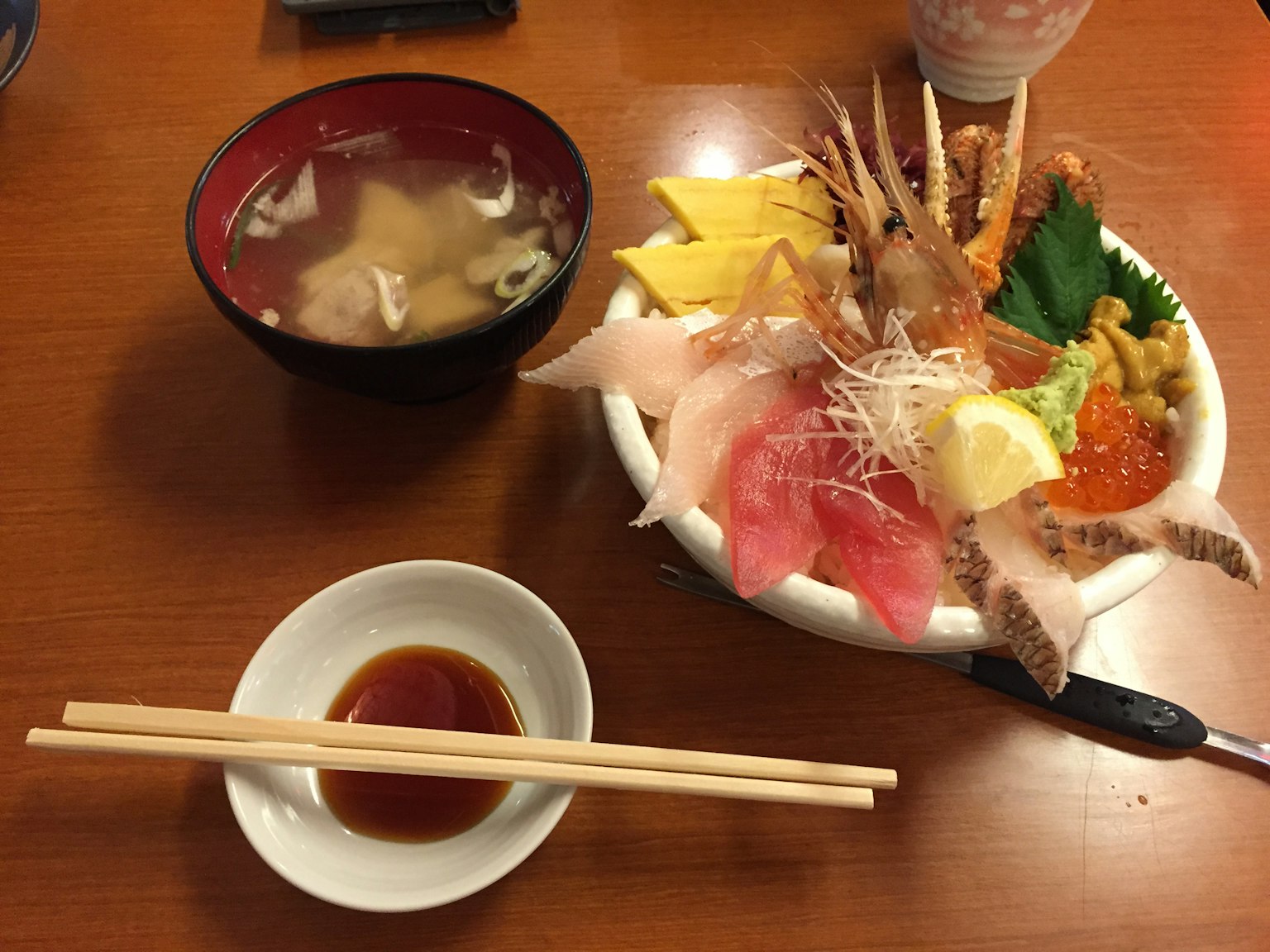 Schön angerichteter Teller mit frischem Sashimi, Miso-Suppe und Sojasauce