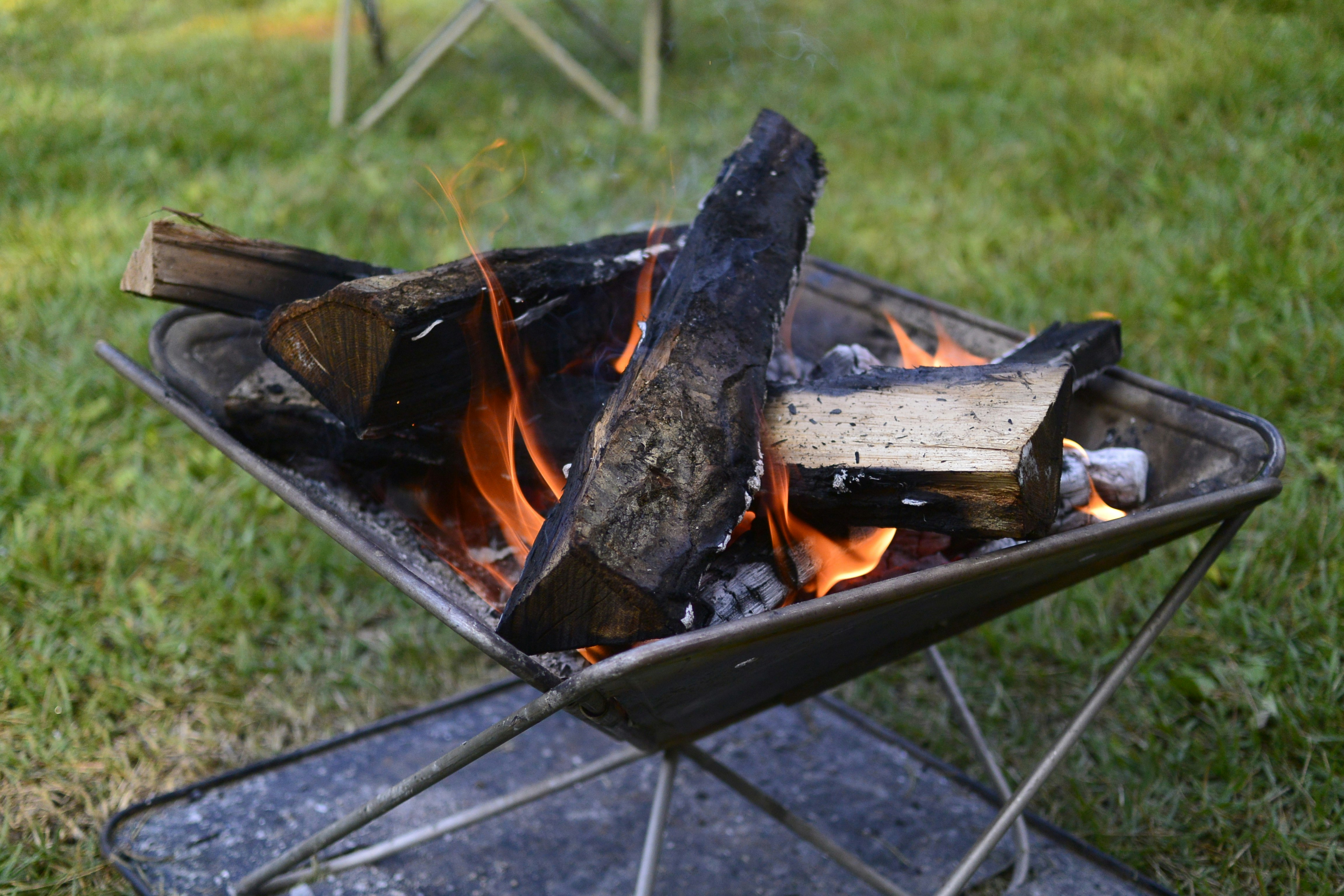 Fuoco che brucia in un braciere con sfondo di erba verde