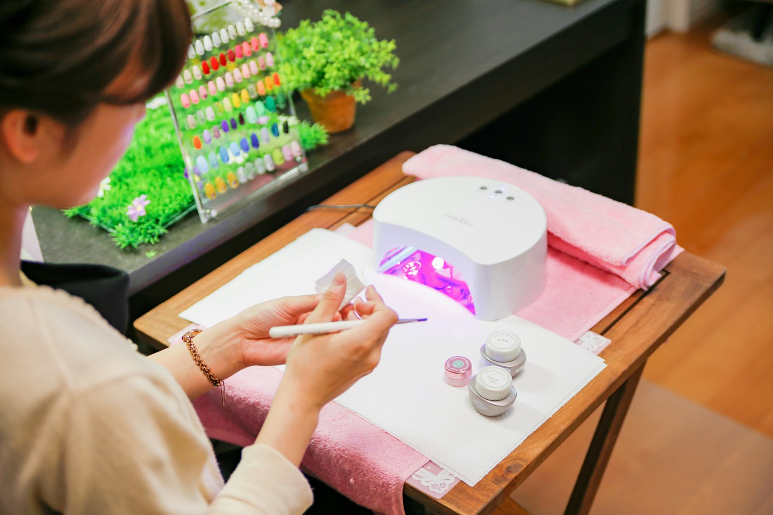 Una donna che fa un nail art sotto una luce LED viola