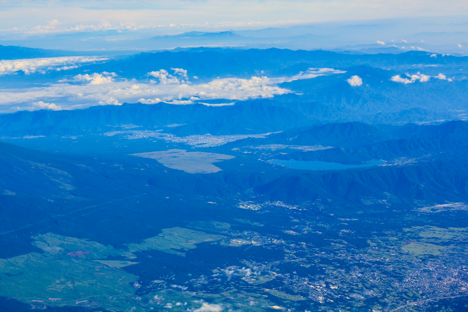 Vista aérea de montañas azules y nubes bajo un cielo despejado