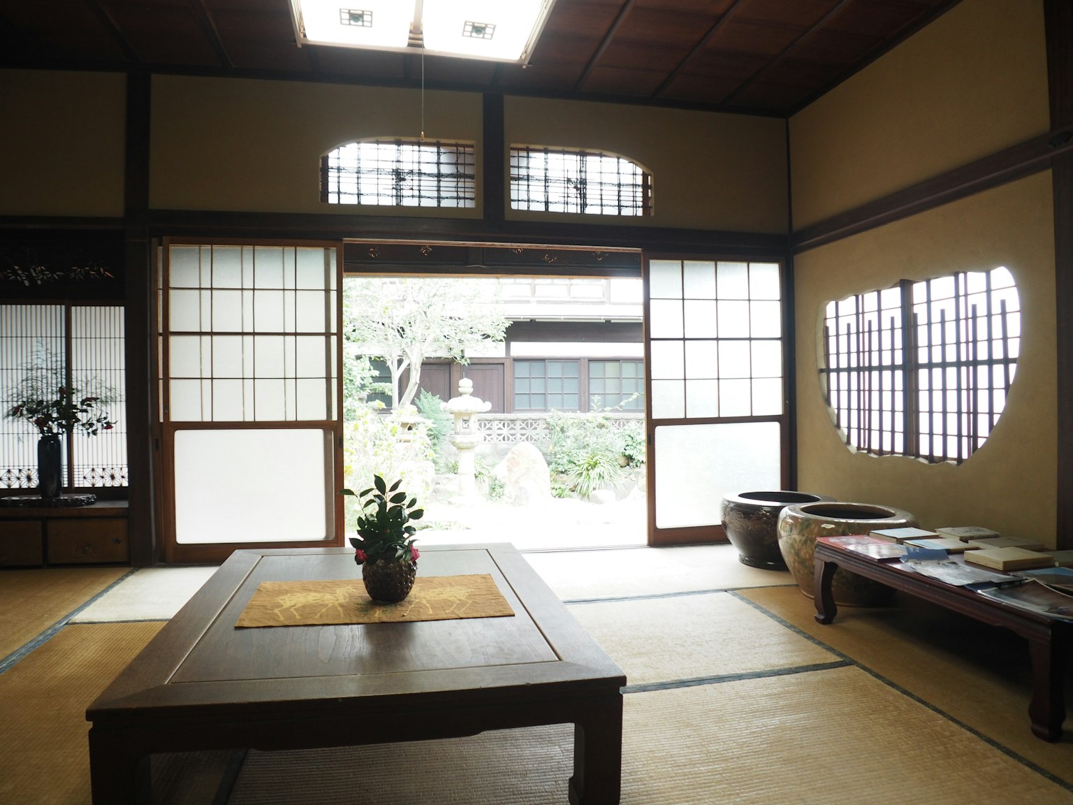 Interior of a traditional Japanese room with a table and potted plant, shoji screens and garden view