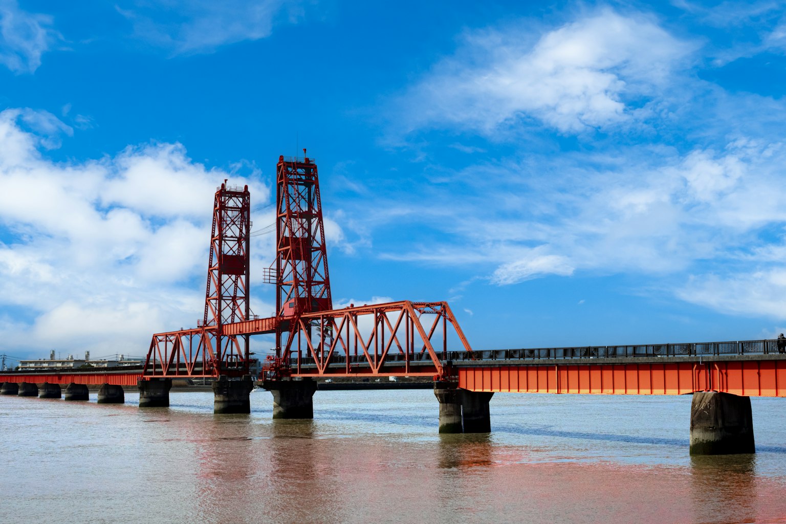 Jembatan merah yang melintasi air di bawah langit biru