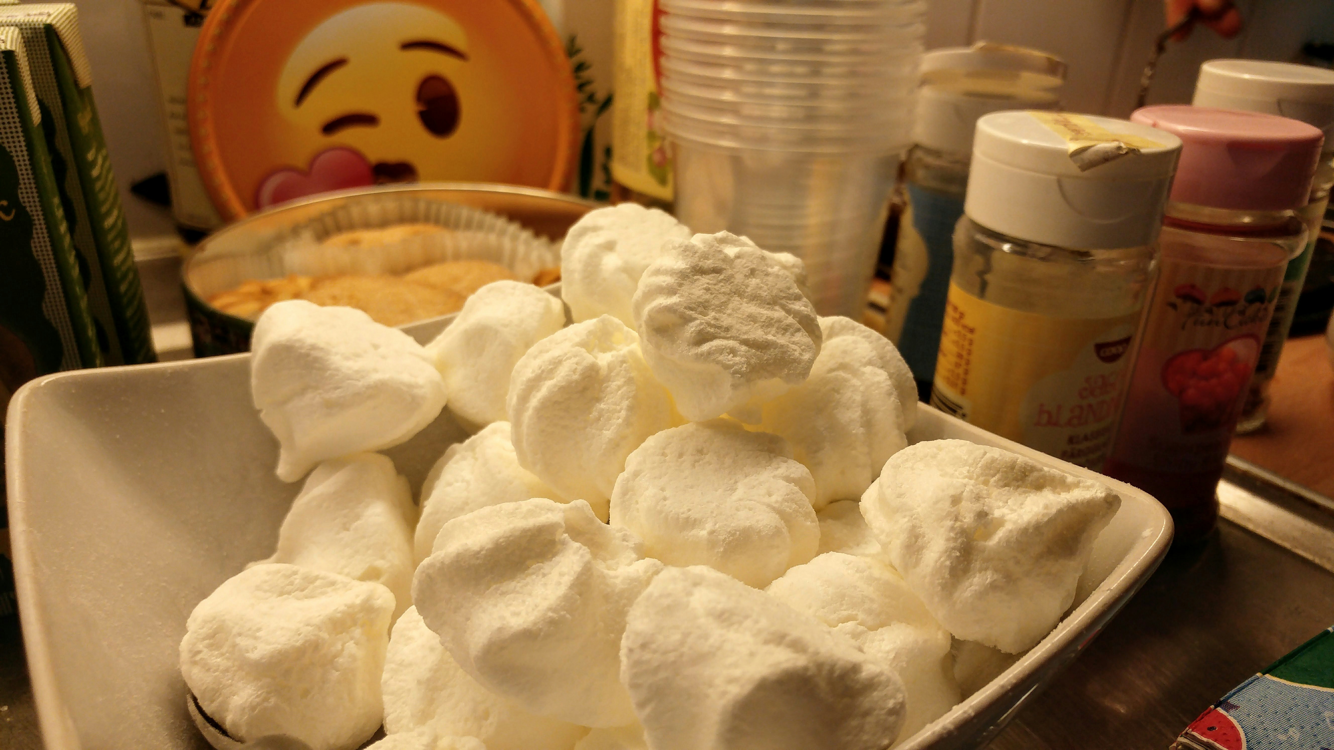table with a pile of white cotton candy and paper cups