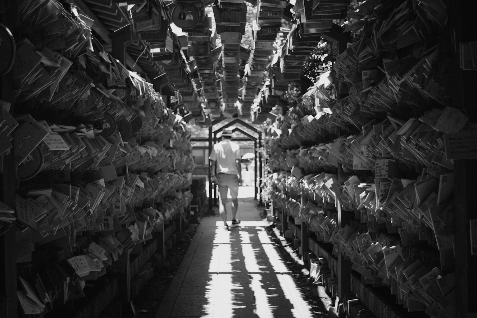 Persona caminando por un pasillo estrecho lleno de documentos en blanco y negro