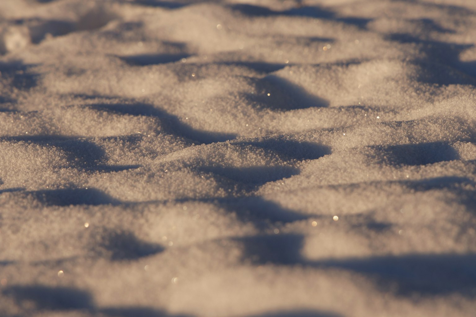 Close-up of a snow surface with glimmering particles and wavy patterns