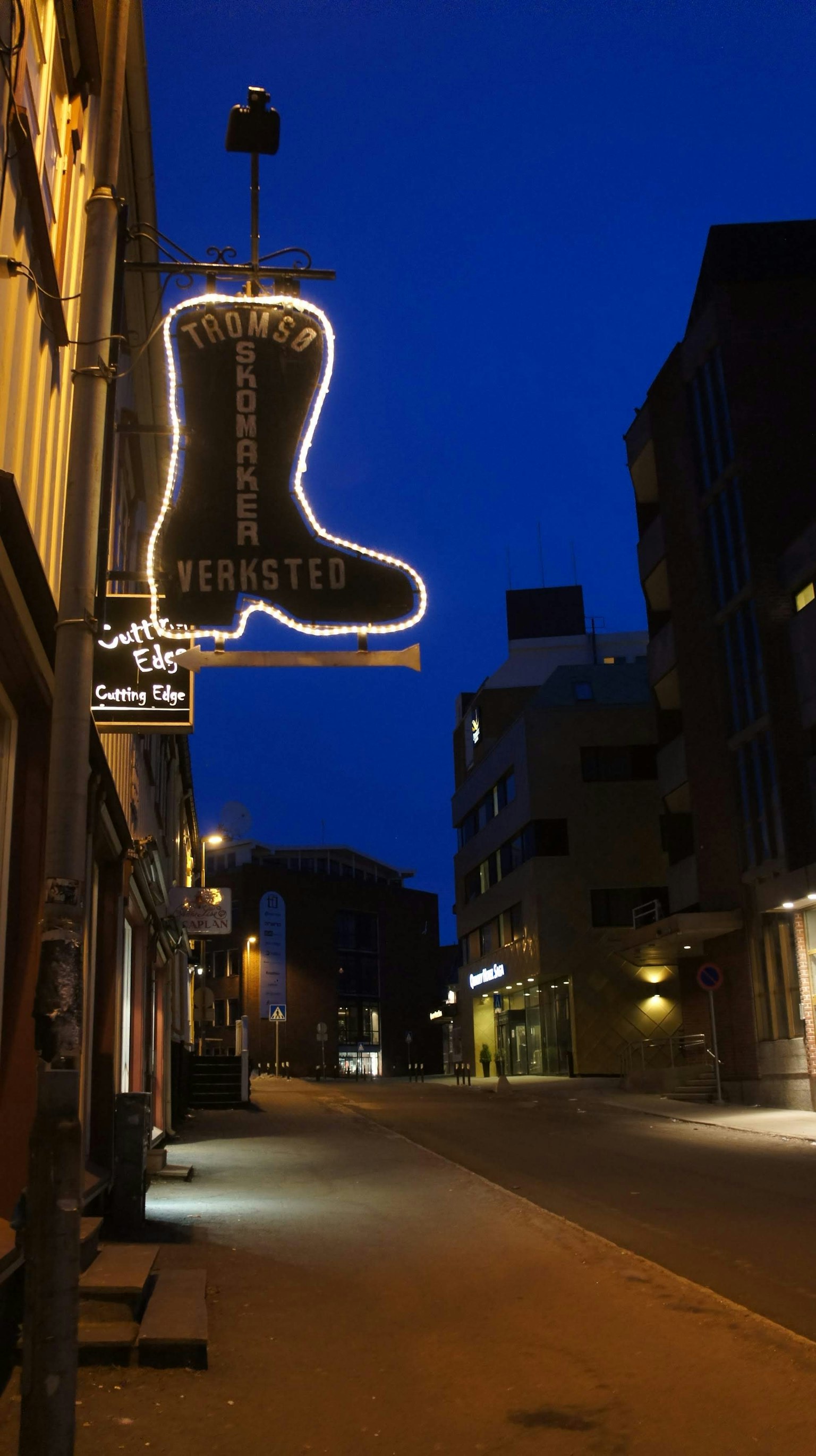 Grand panneau néon en forme de botte illuminé la nuit dans une rue calme