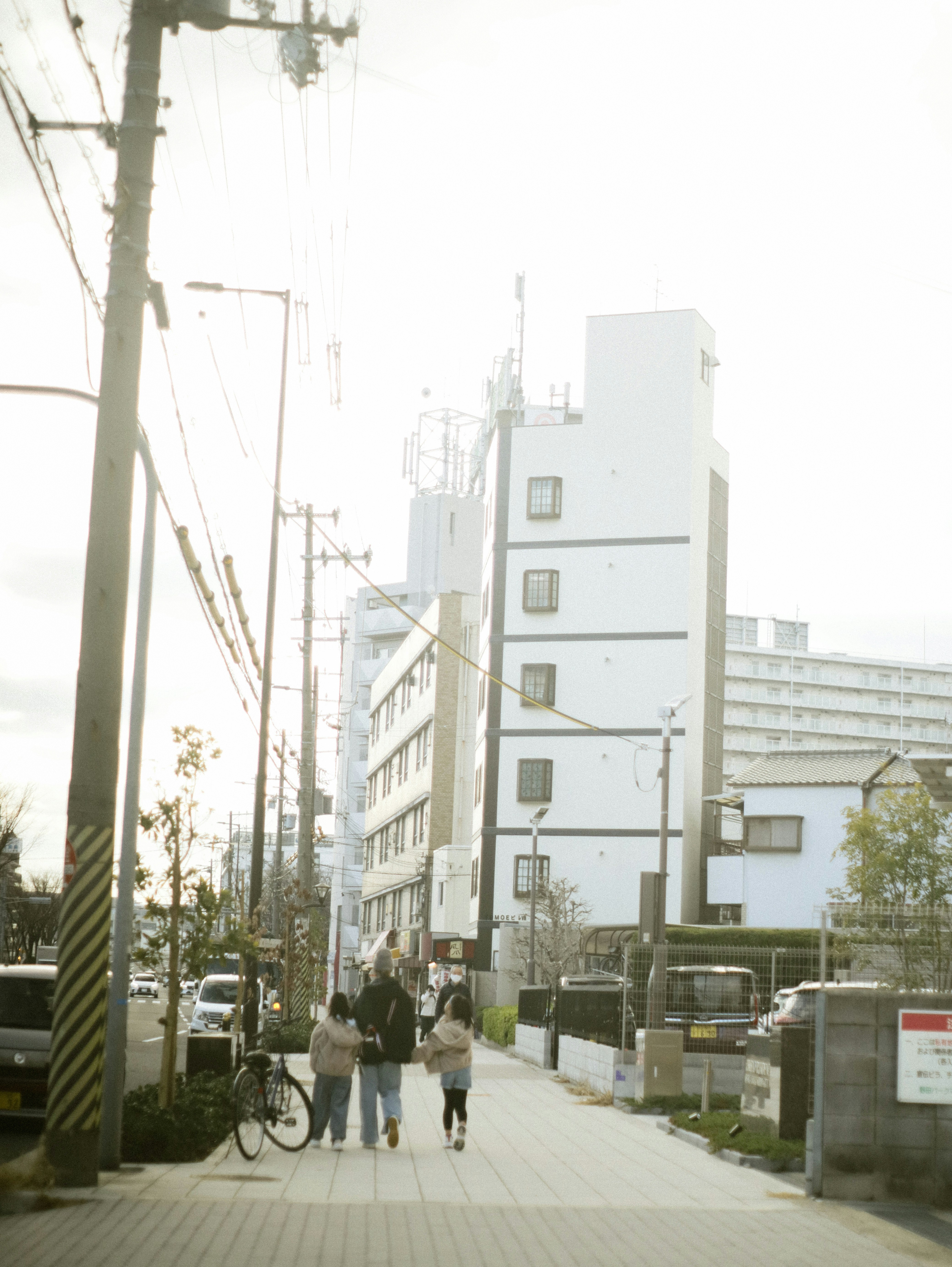 人々が歩いている街の風景 白い建物と電柱が並ぶ