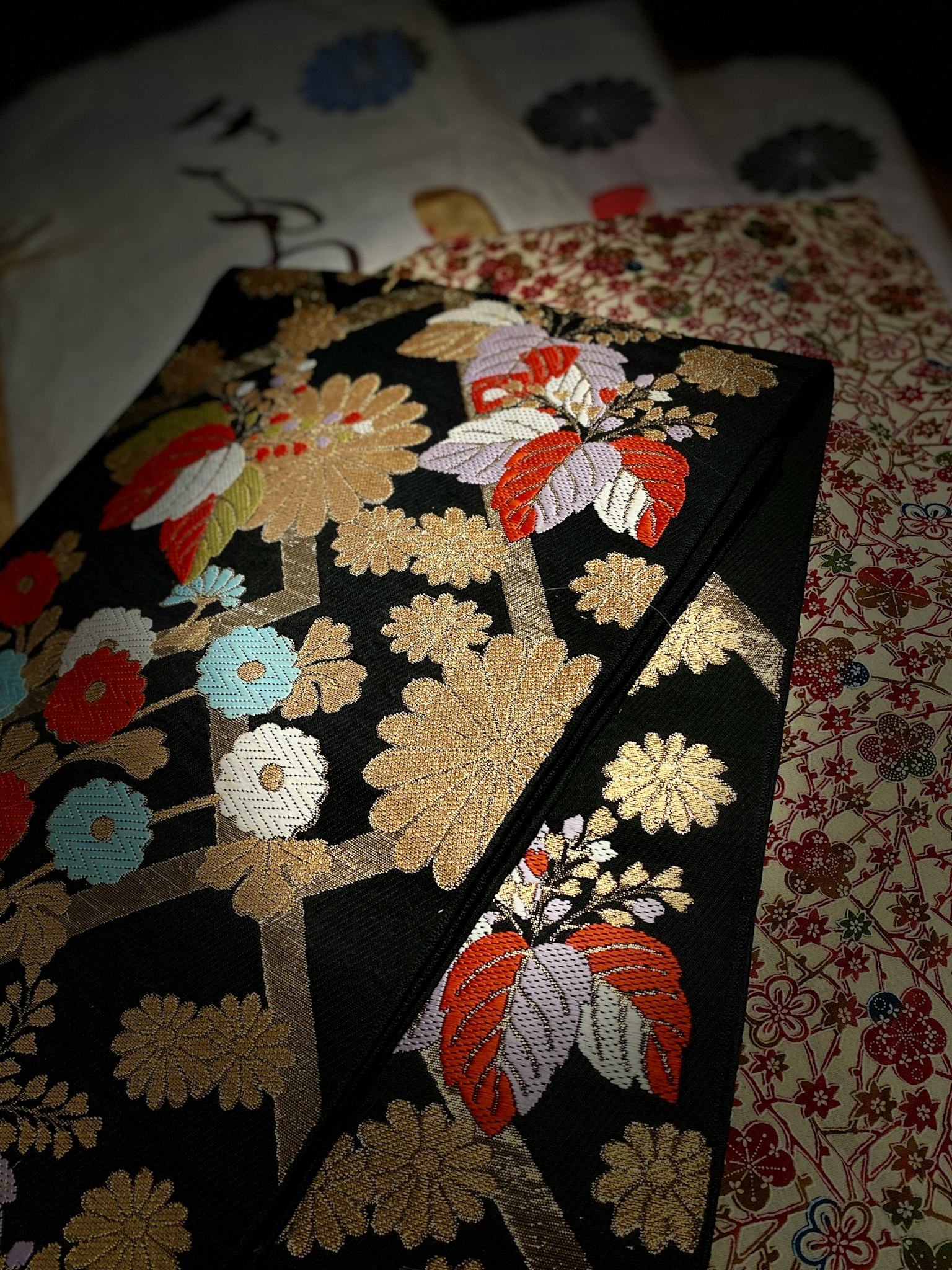 Kain kimono bermotif bunga berwarna di latar belakang hitam