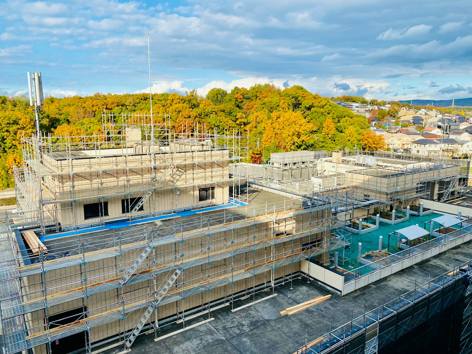 Chantier de construction avec échafaudage autour d'un bâtiment et des arbres d'automne en arrière-plan