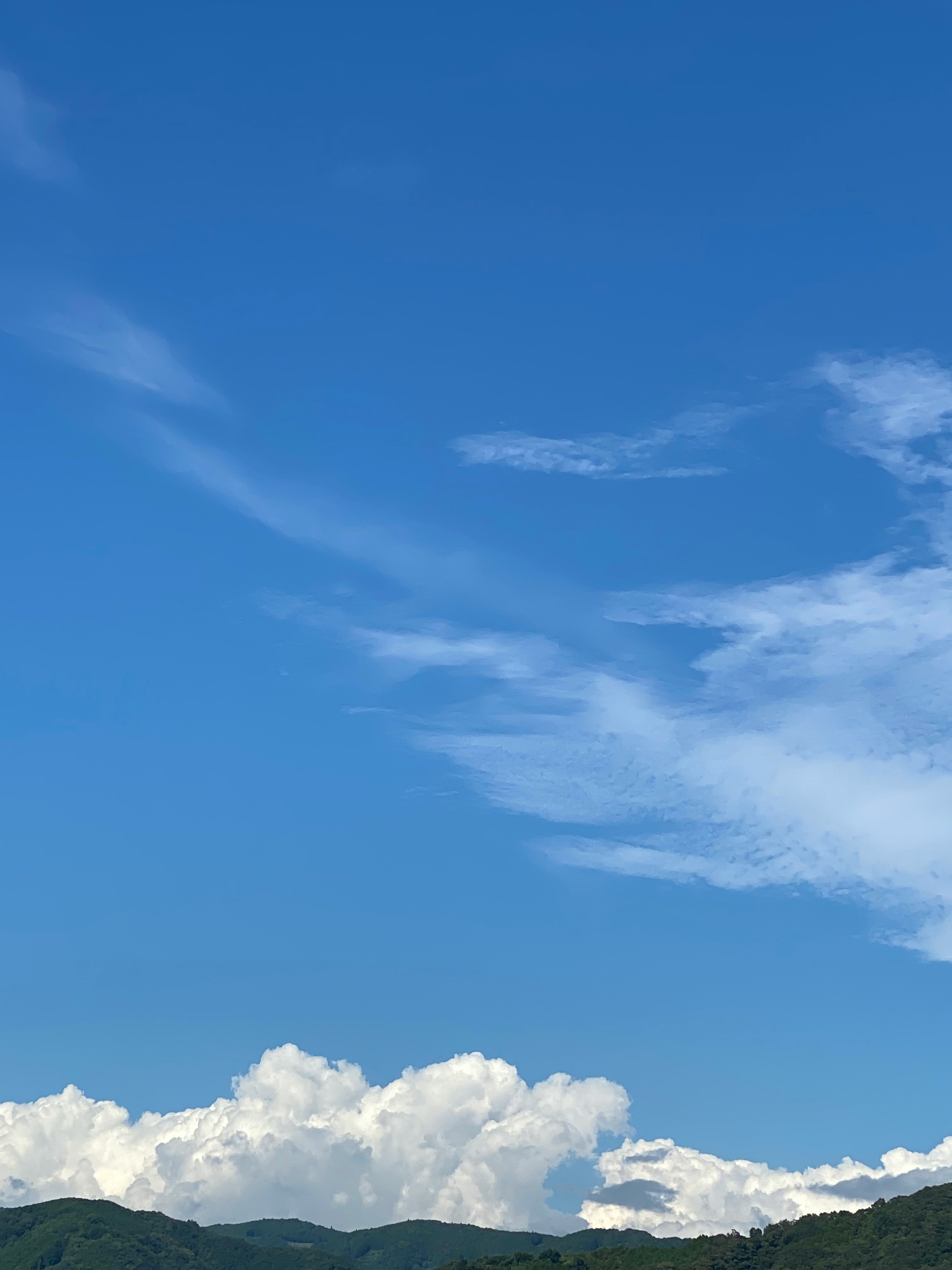 cordillera verde bajo un cielo azul con nubes