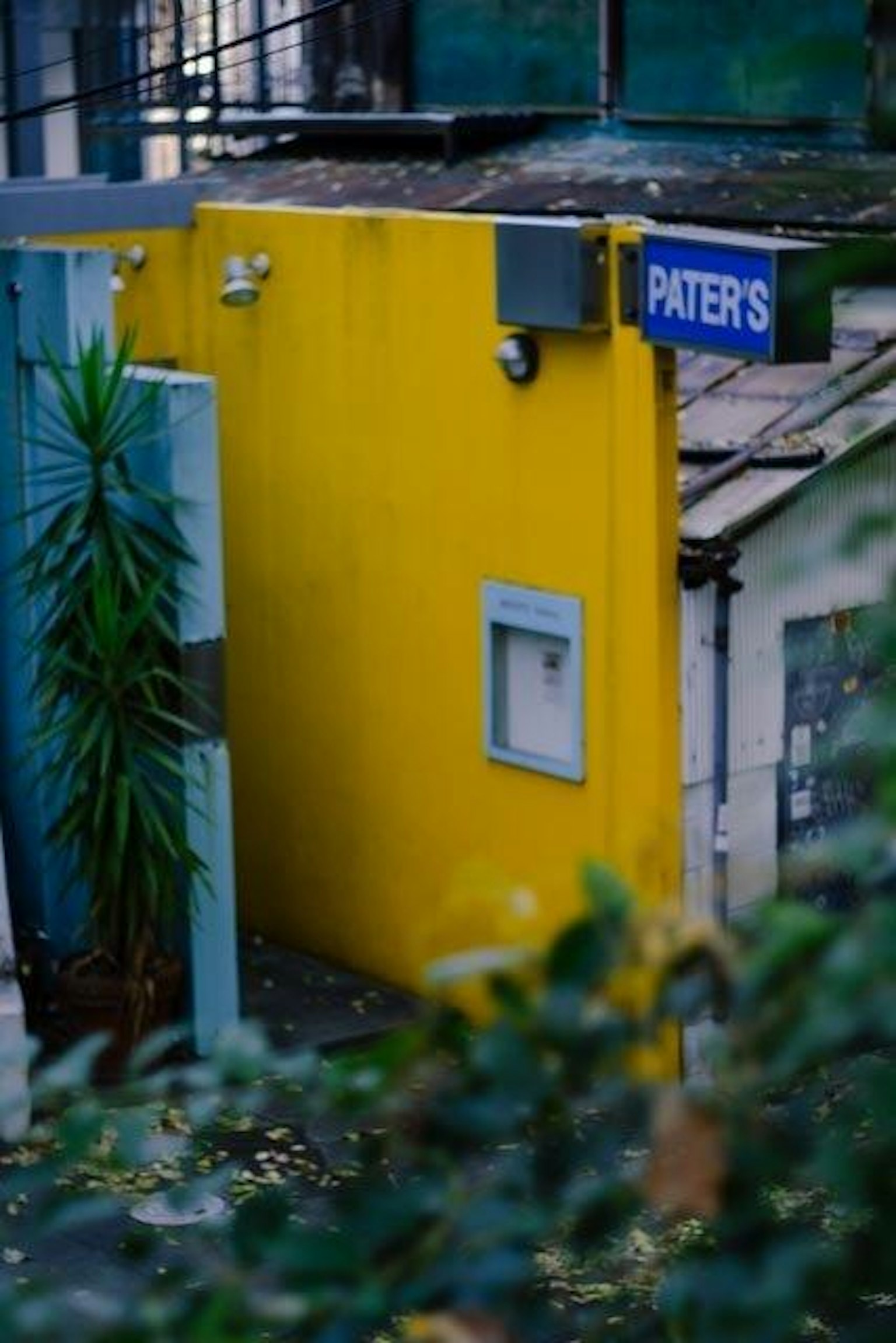 Entrada de un edificio con pared amarilla y letrero azul