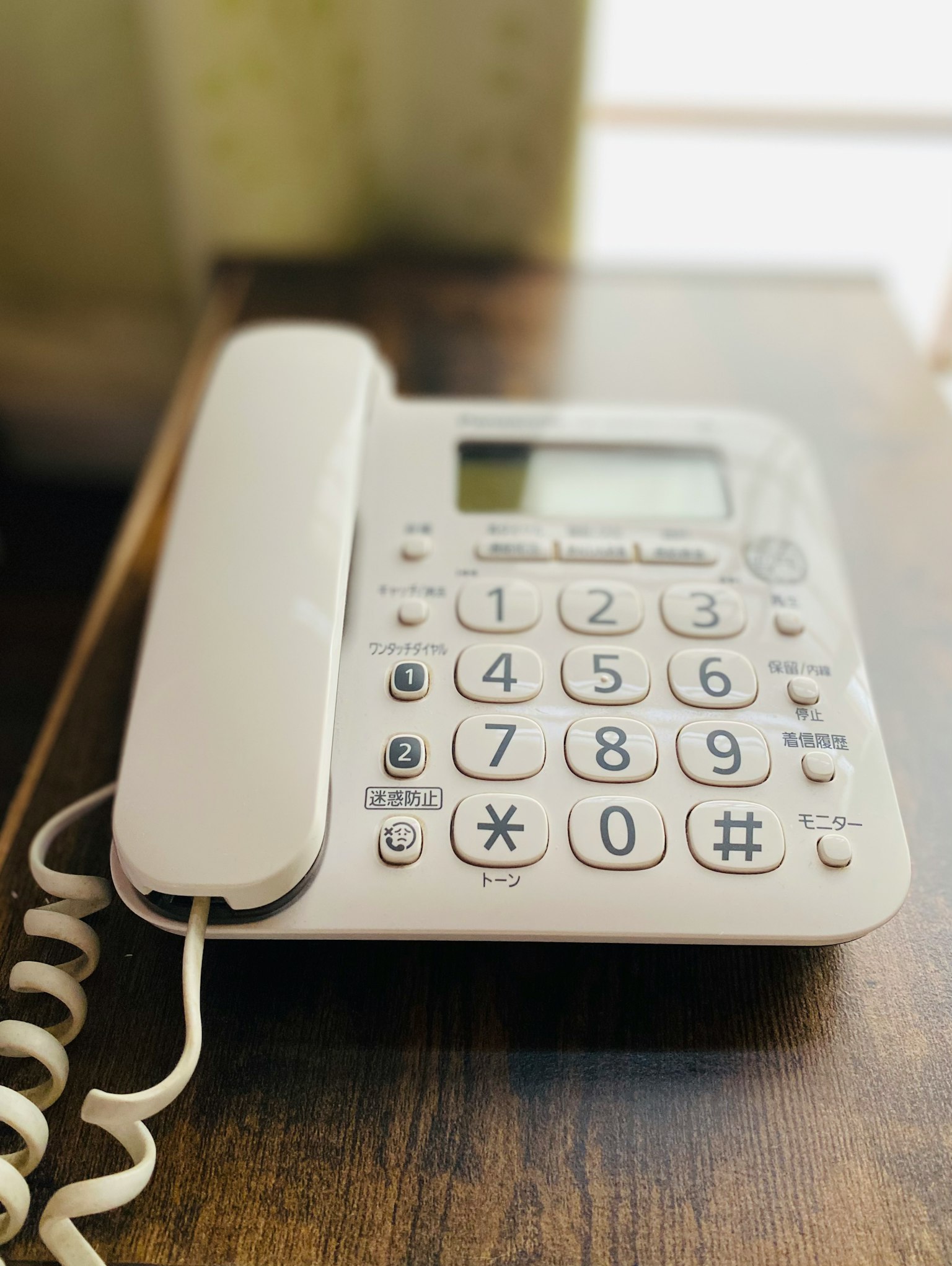 A white telephone placed on a wooden table