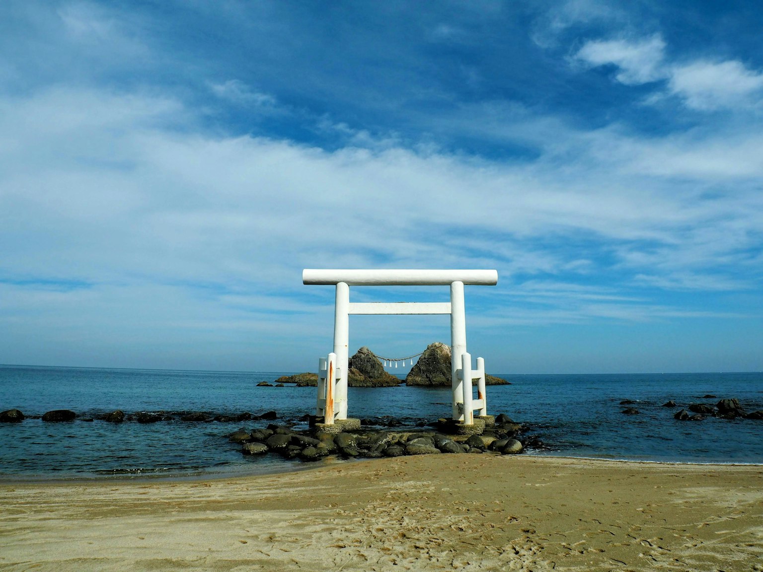Un cancello torii bianco circondato da cielo blu e oceano