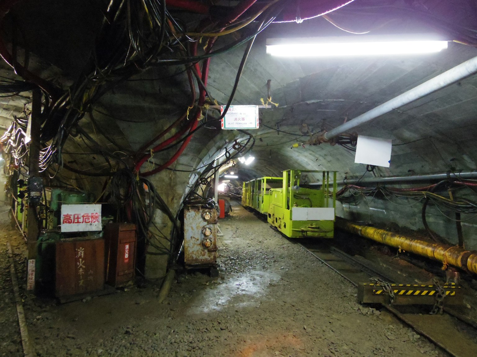 Interno di un tunnel sotterraneo con un veicolo giallo e cablaggi visibili