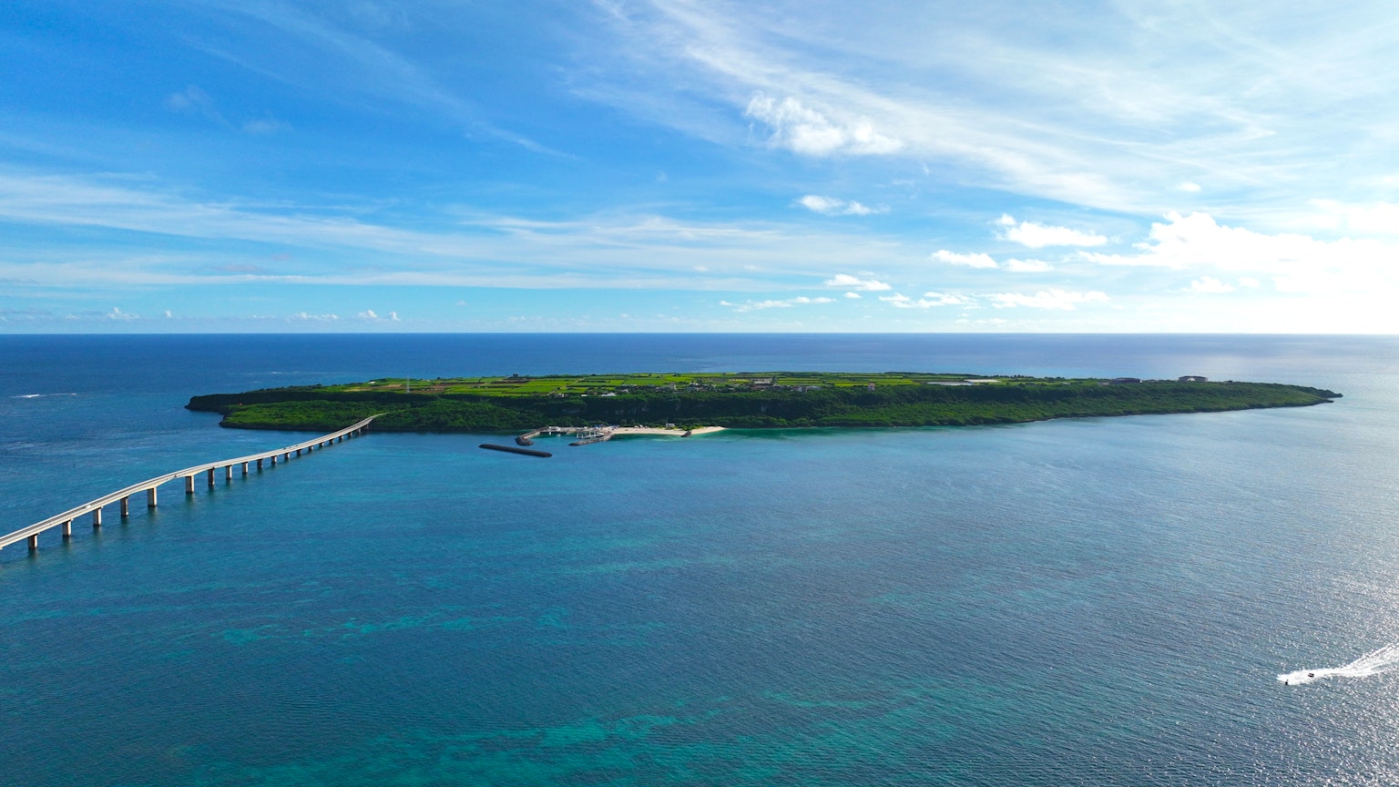 เกาะสีเขียวล้อมรอบด้วยมหาสมุทรสีน้ำเงินพร้อมท่าเรือยาว