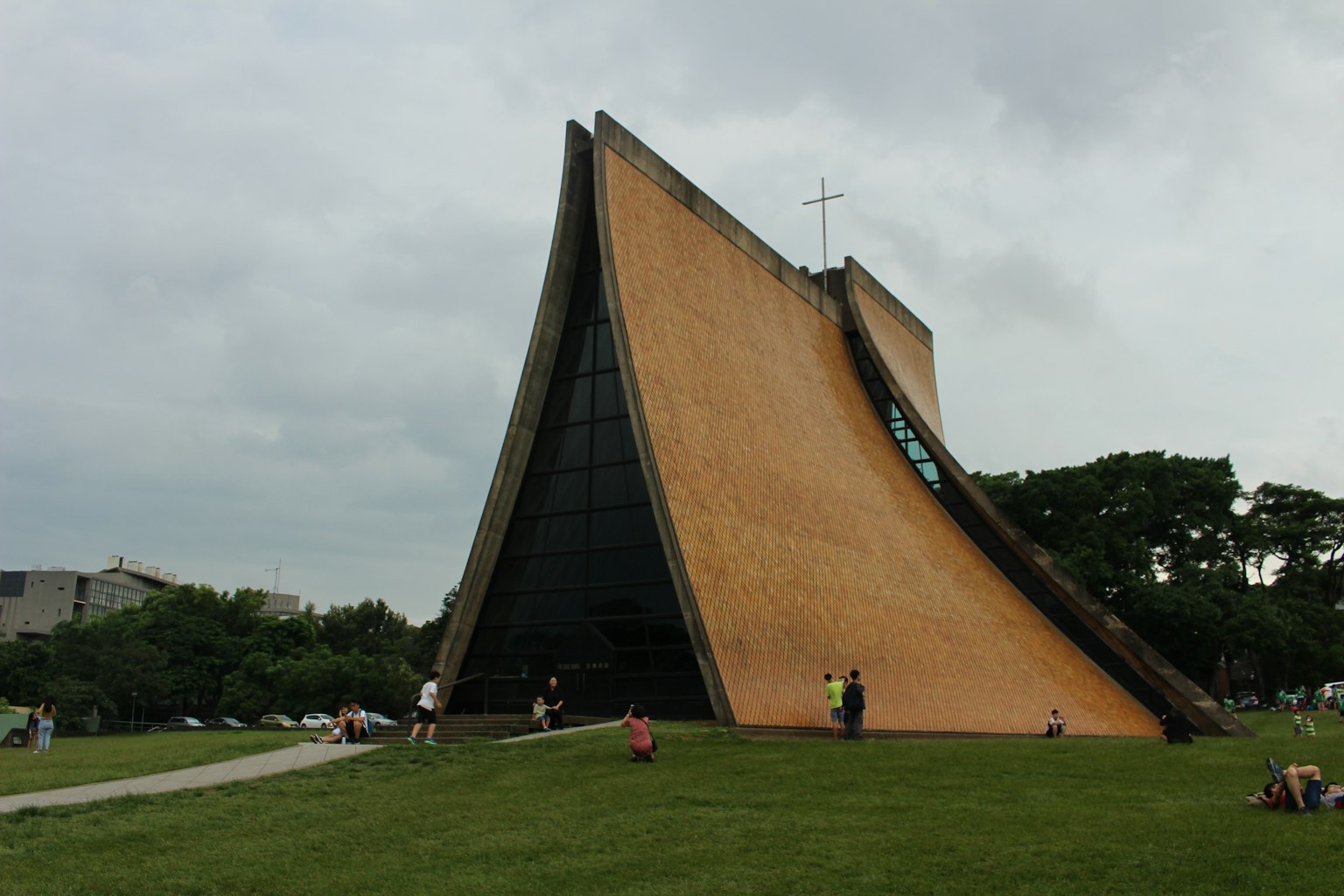 Modern church exterior with a slanted roof featuring people engaged in activities around
