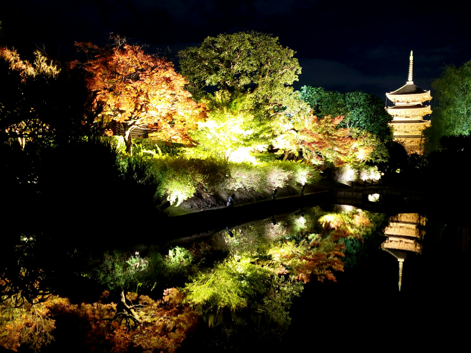 การสะท้อนที่สวยงามของใบไม้ฤดูใบไม้ร่วงและเจดีย์ที่ส่องสว่างในสวนกลางคืน
