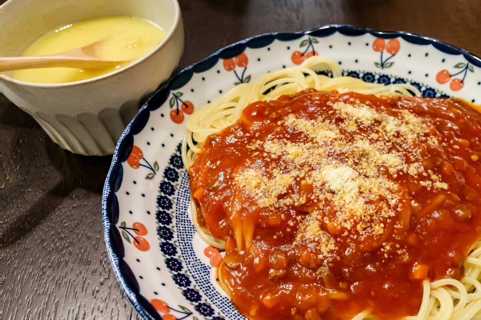 Piring spaghetti dengan saus tomat dan mangkuk pencuci mulut krim