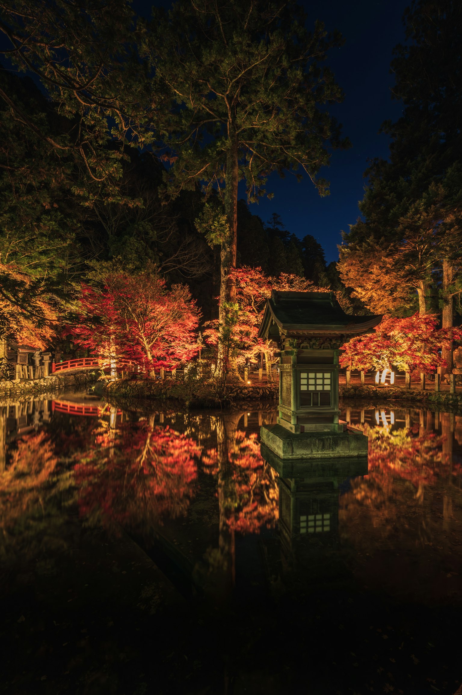Beau feuillage d'automne et petit bâtiment reflétés dans un étang nocturne