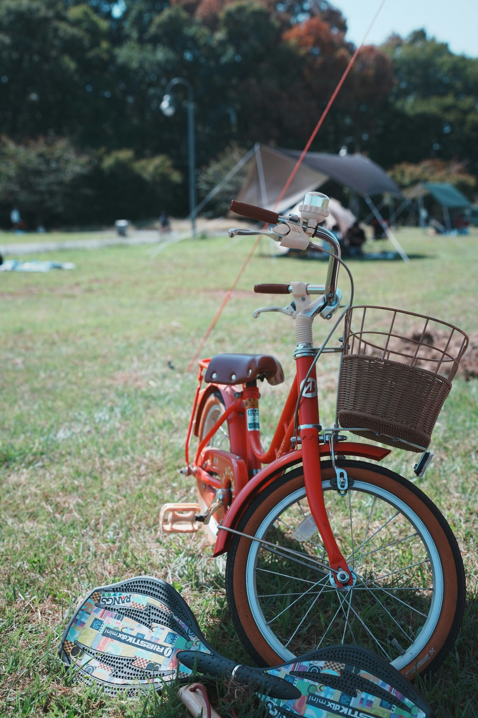 草地に停められた赤い自転車とカゴ