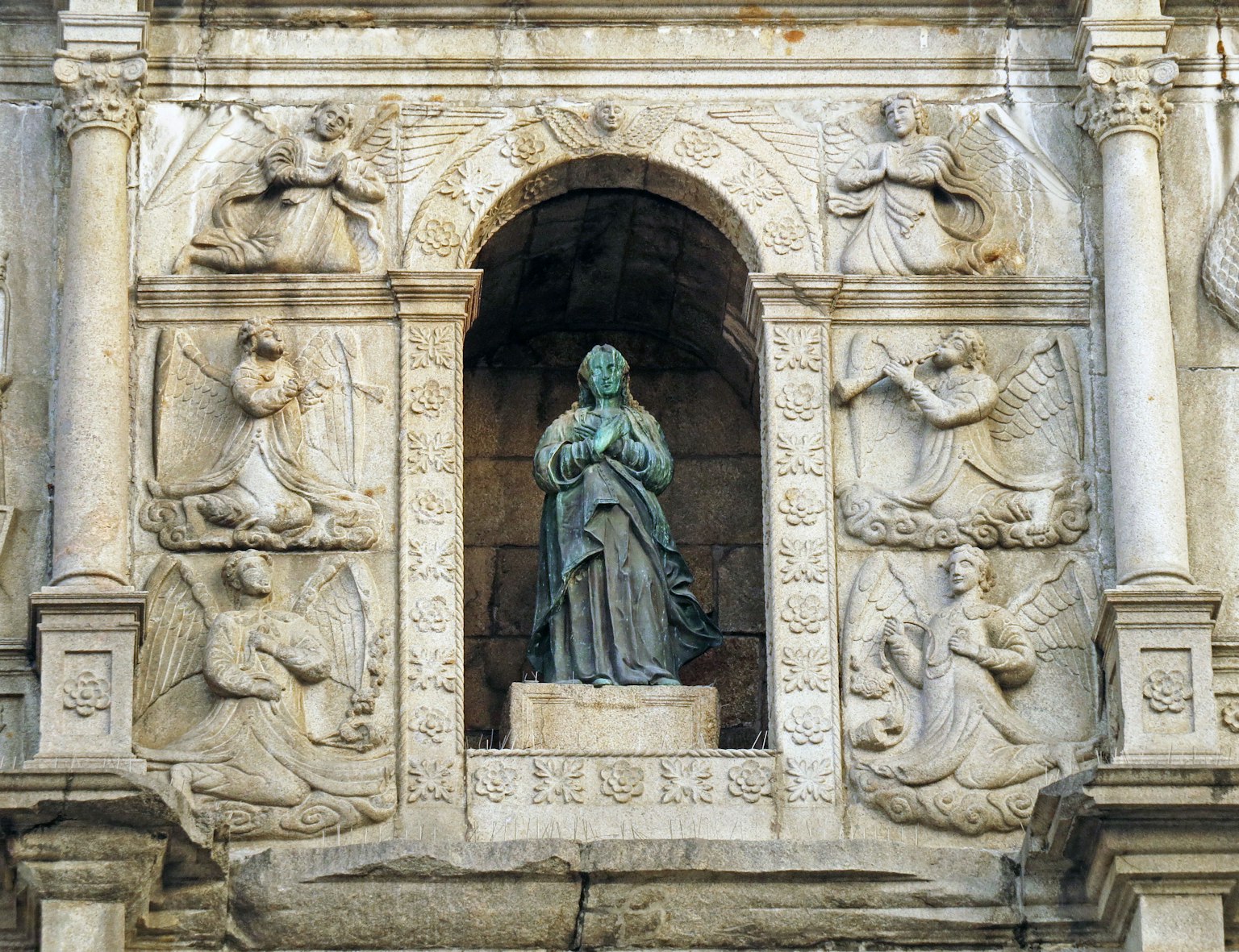 Statue de la Vierge Marie dans une façade en pierre avec des sculptures détaillées