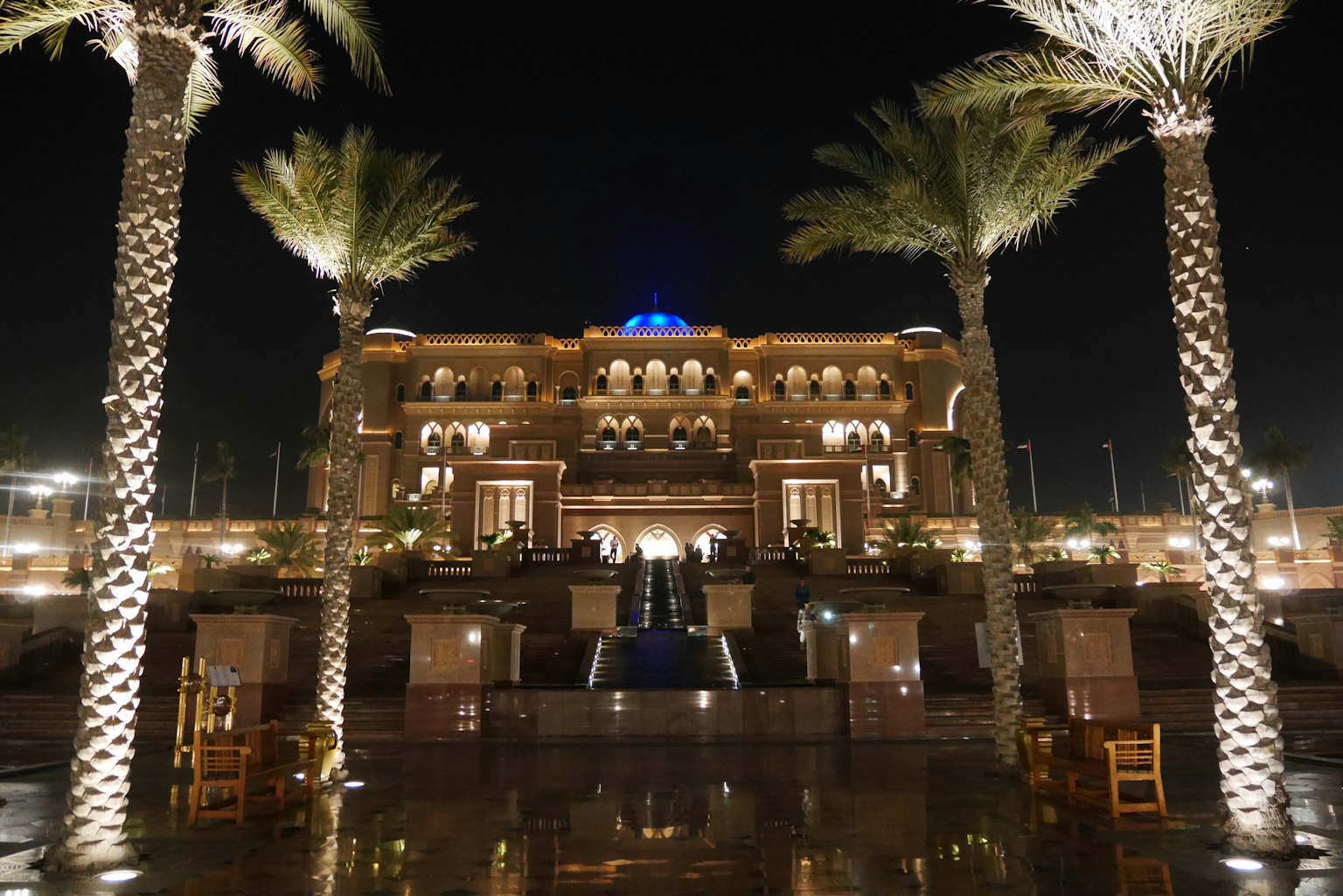 Illuminated palace exterior at night with palm trees