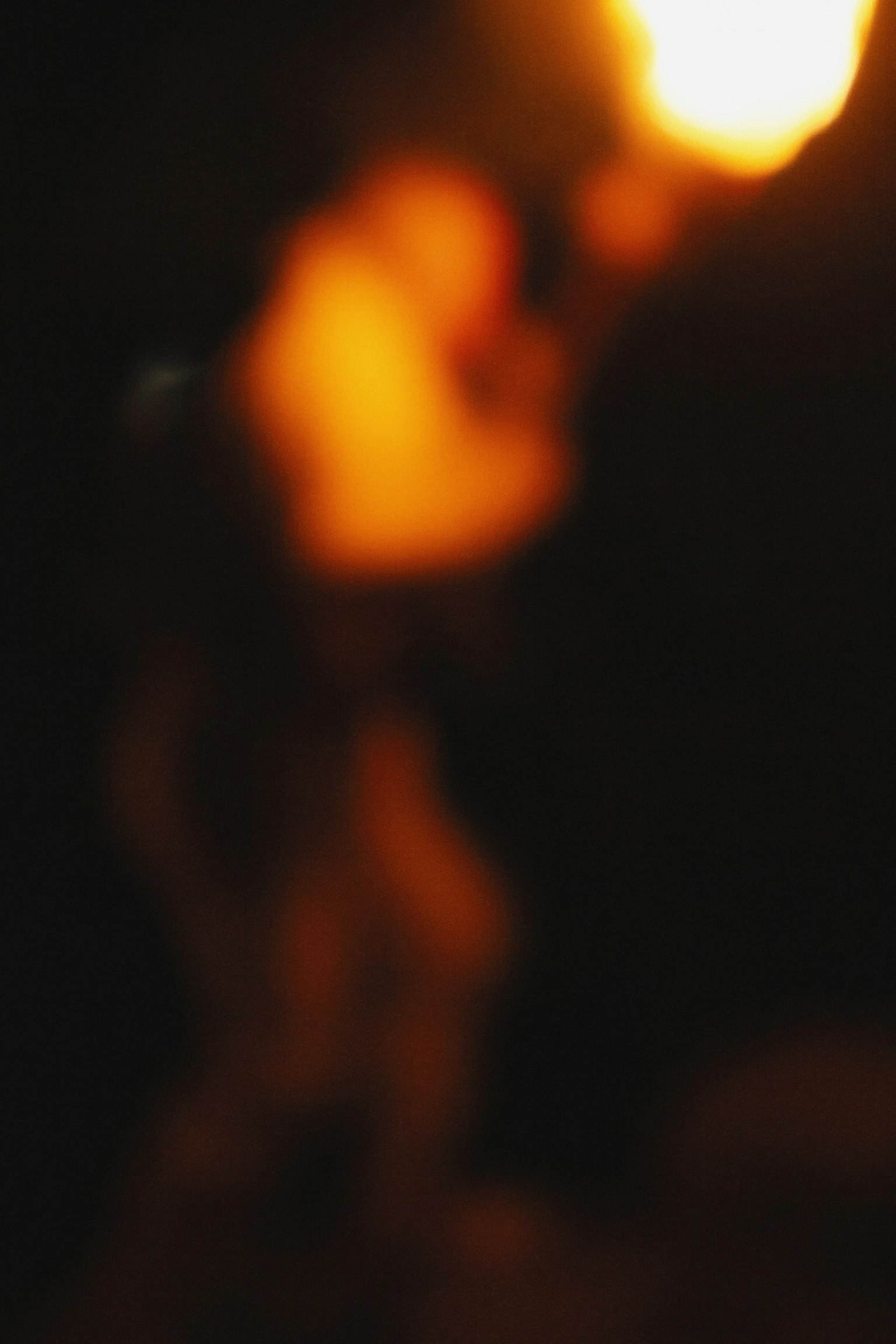 Silhouette sfocata di una persona che tiene una fiamma nel buio