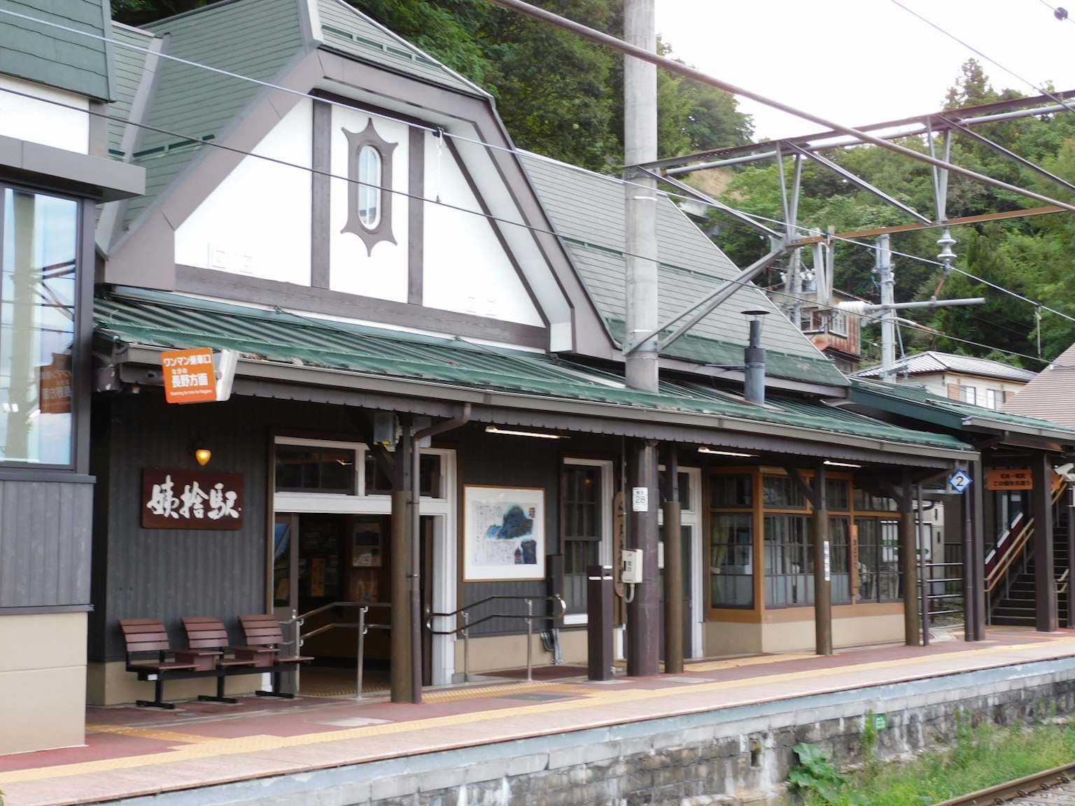 Exterior de una estación de tren japonesa tradicional con techo verde y bancos