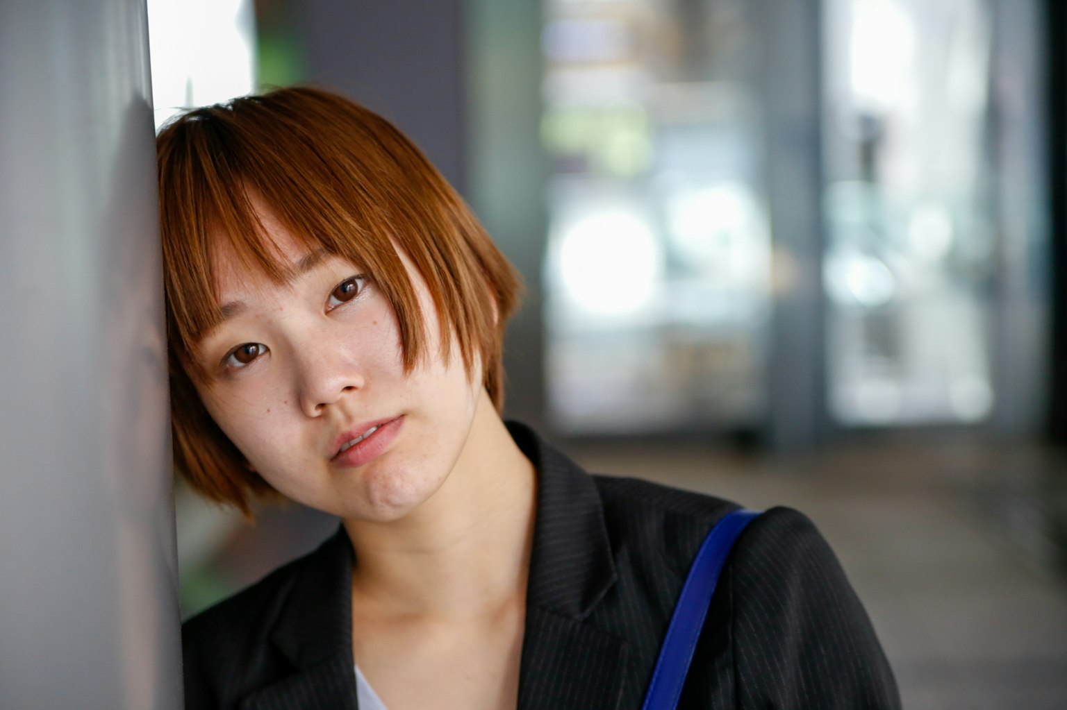 หญิงสาวผมสั้นสีน้ำตาล leaning against a wall ดูเหมือนกำลังคิด