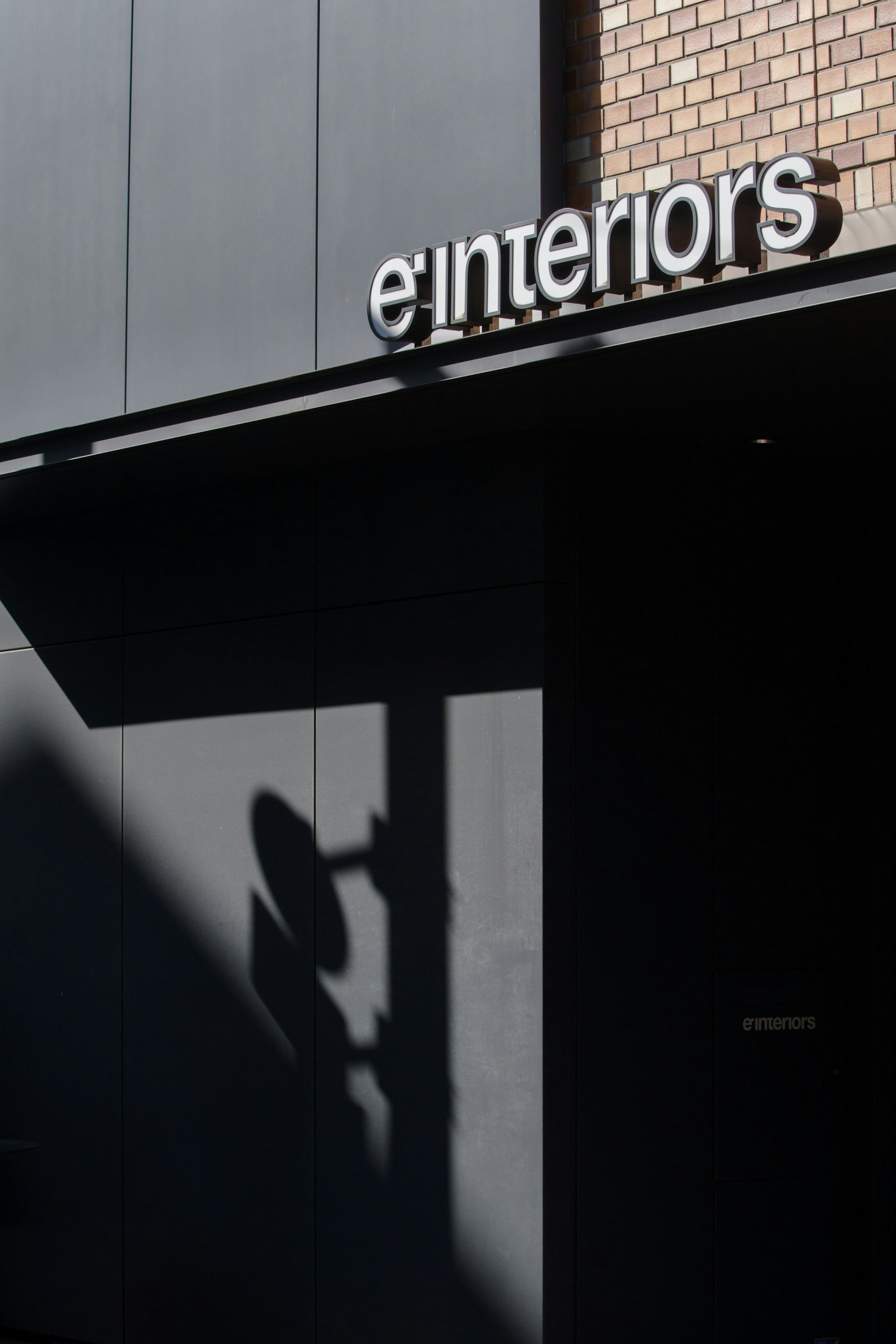 cartel de e'interiors en un exterior oscuro con una sombra proyectada