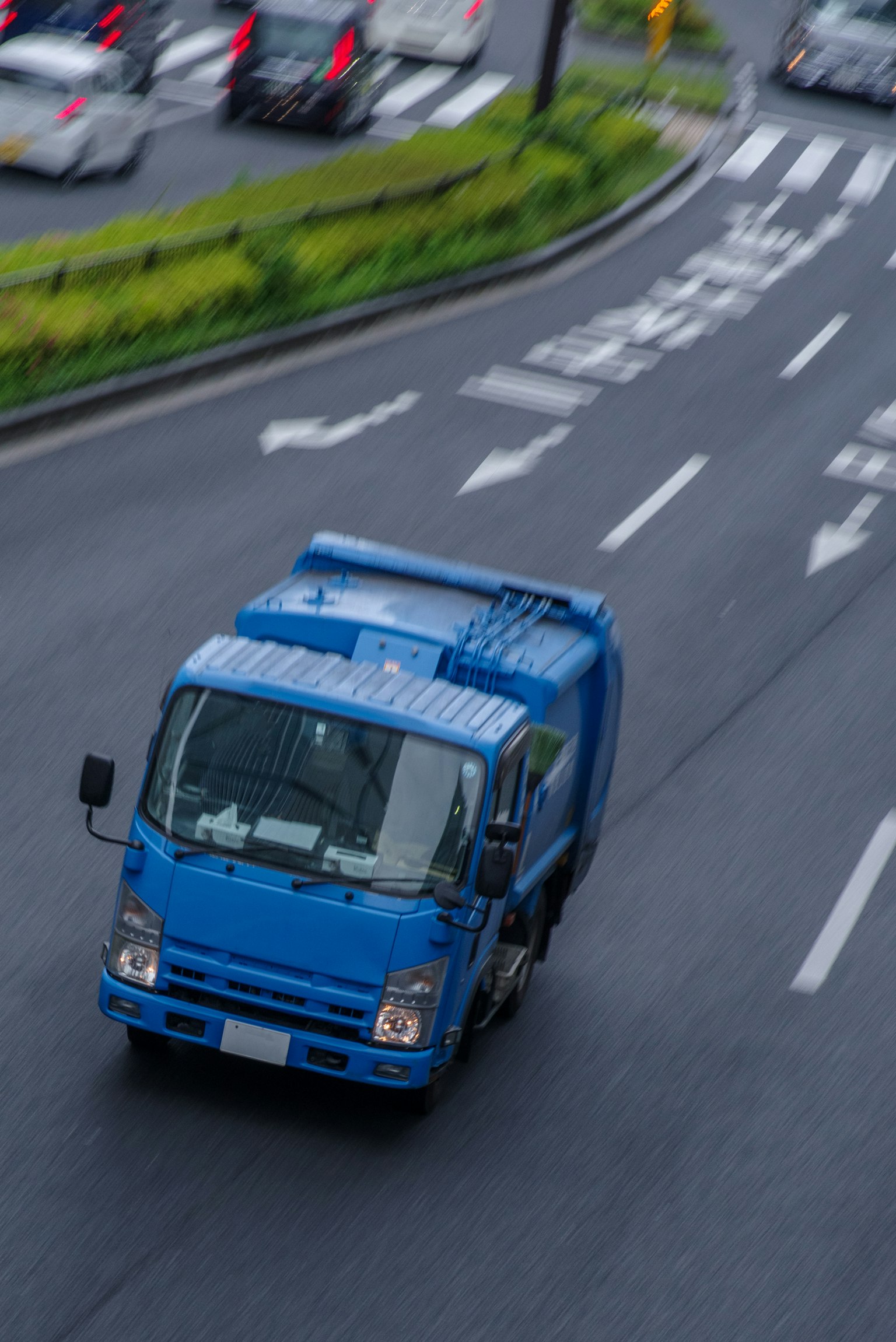 Sebuah truk biru melaju di jalan