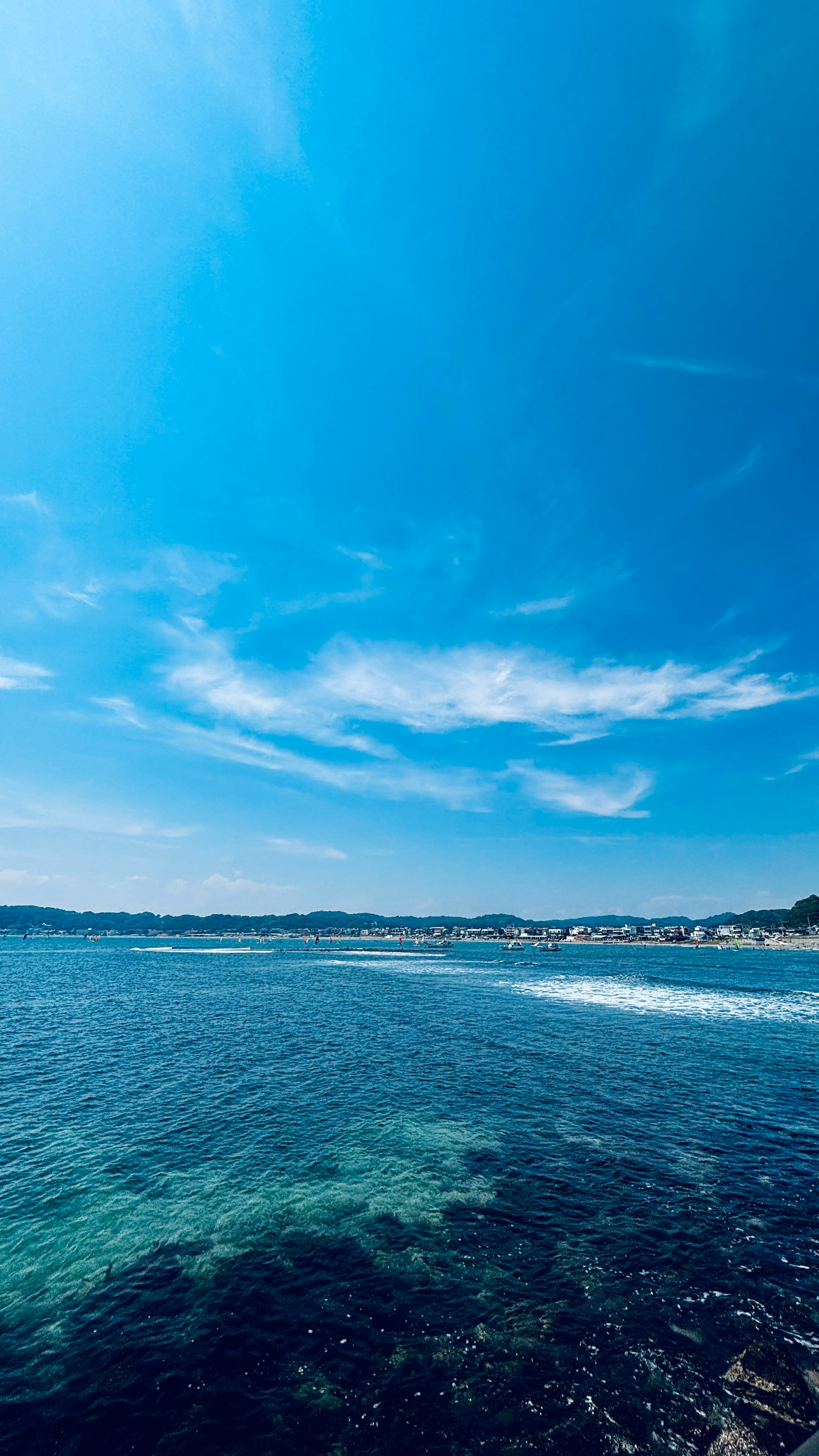 青い空の下の海岸線と波のある海の風景