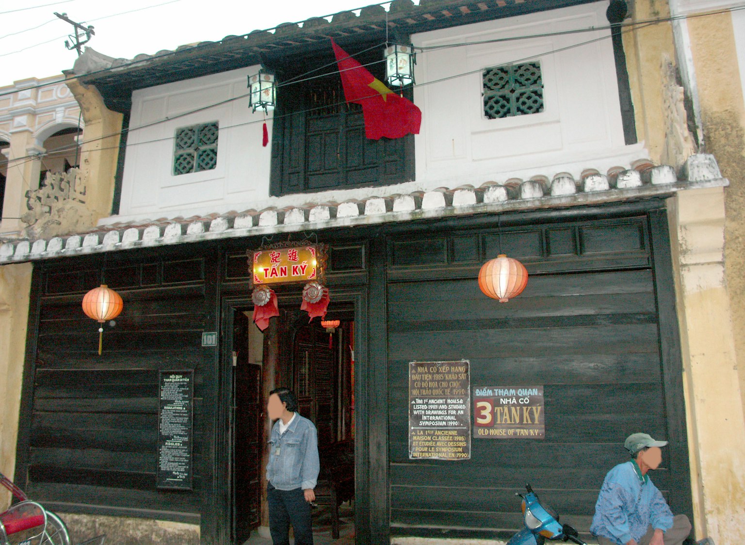 Fachada de una casa antigua con decoraciones rojas y faroles