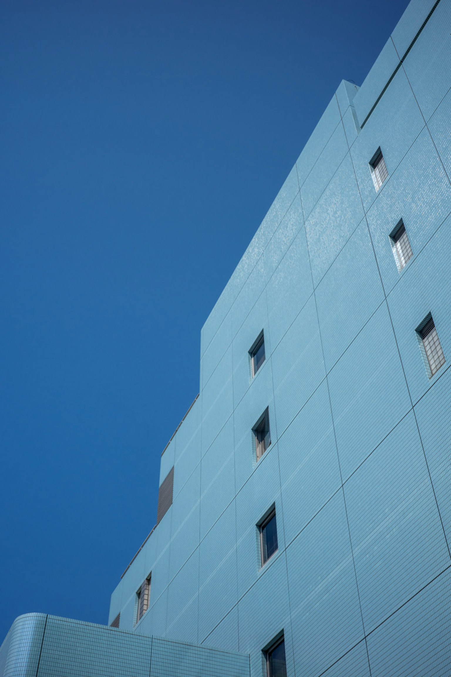 Vista lateral de un edificio azul contra un cielo azul claro