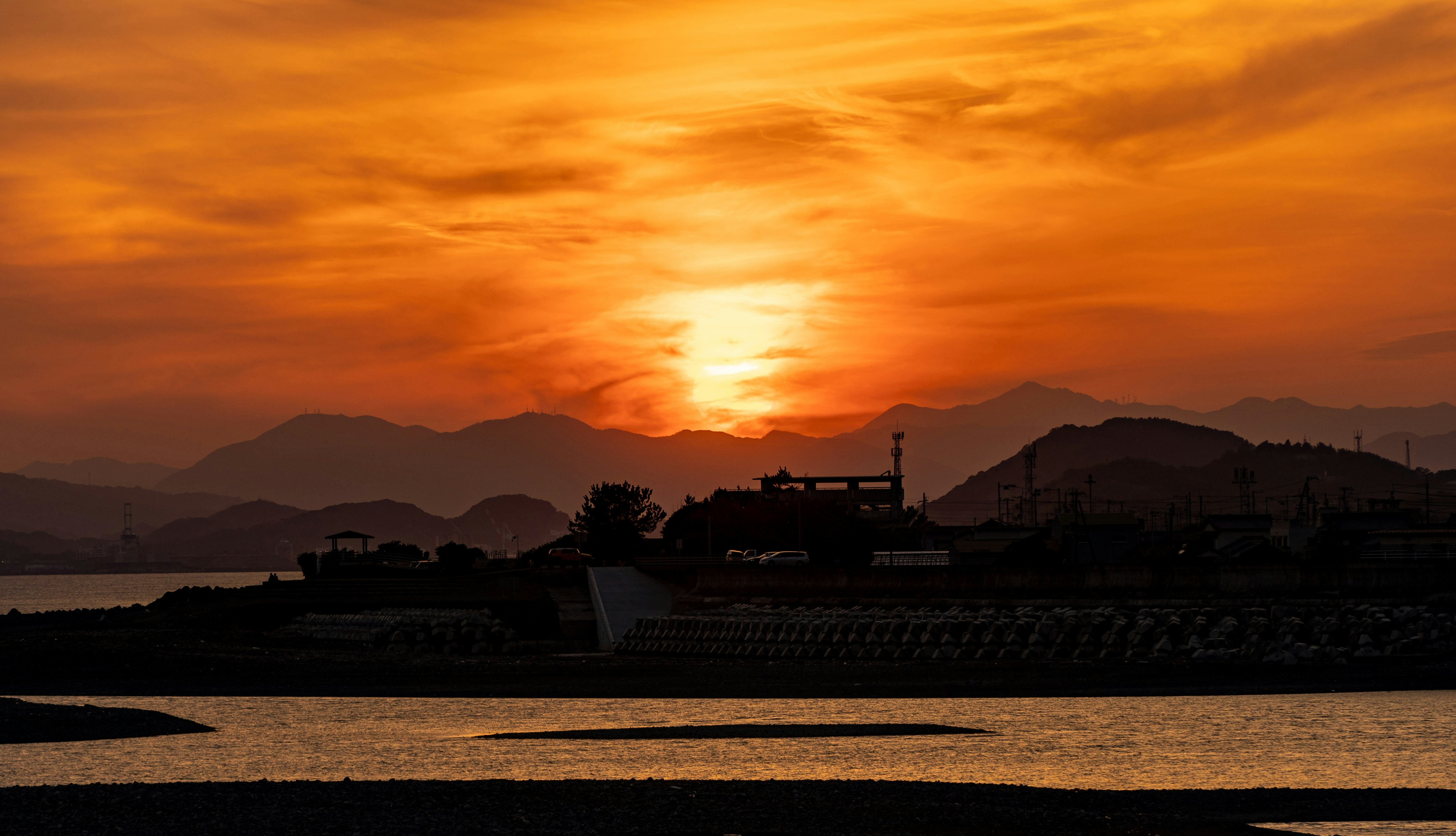 夕焼けの海辺と山並みのシルエット