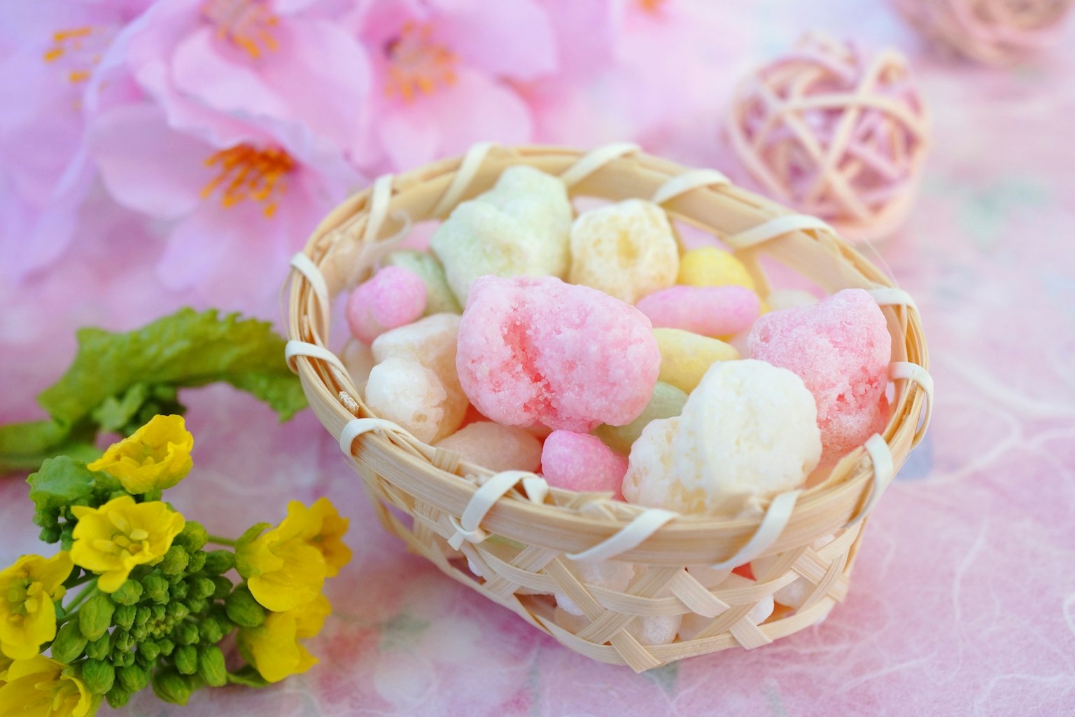 Un piccolo cesto pieno di caramelle colorate su uno sfondo floreale
