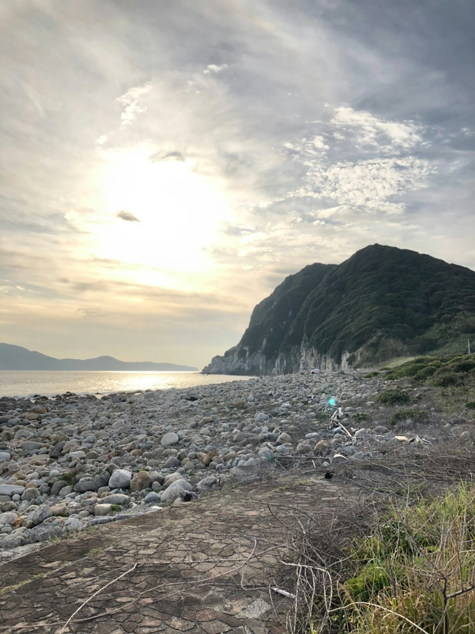 Costa rocciosa con montagne al tramonto che si riflettono sull'acqua
