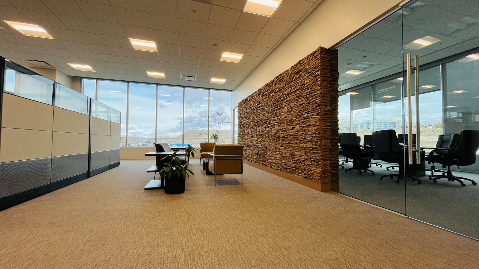 Bright office space with glass walls stone feature wall conference room chairs potted plants