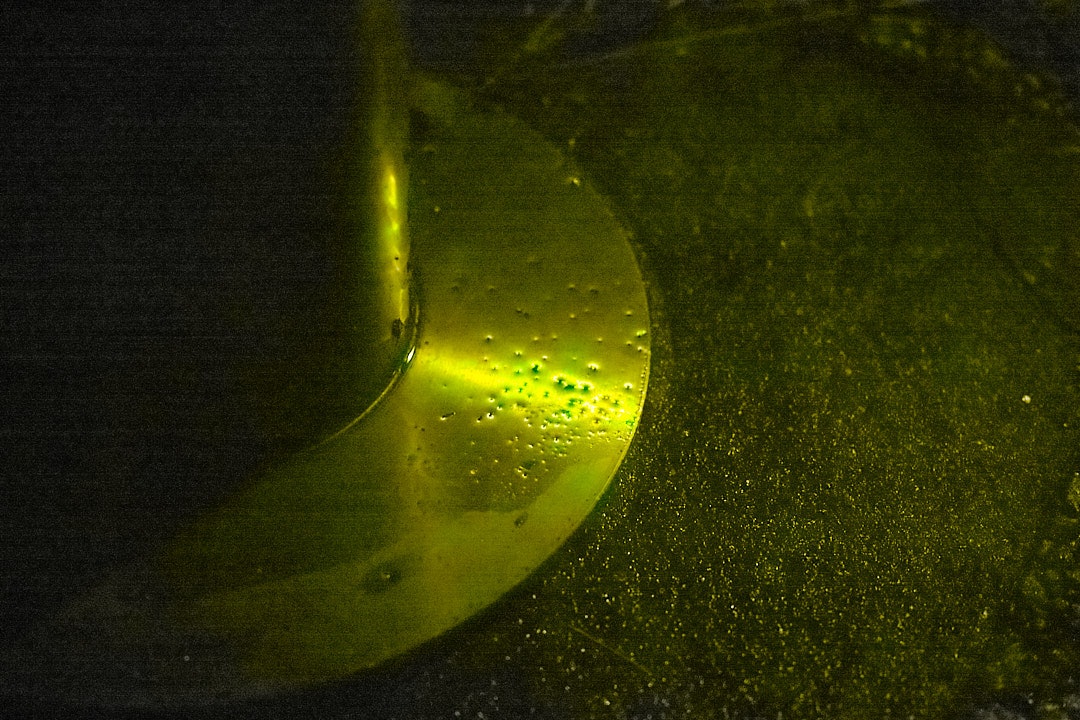 ガラス越しの黄色い液体のしずくと気泡のある抽象的な質感