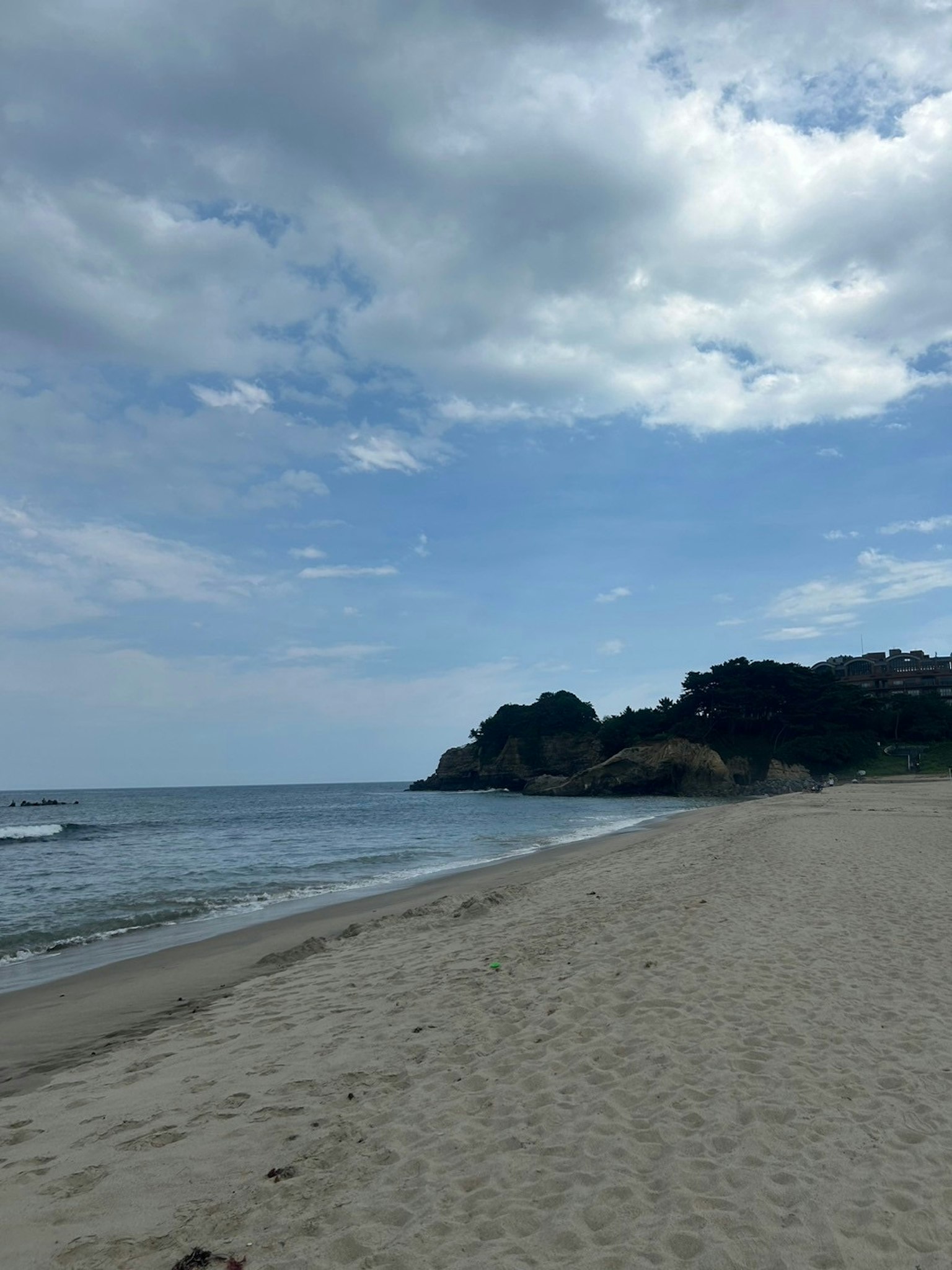 Une scène de plage sereine avec des eaux calmes et une rive sablonneuse Nuages épars dans le ciel