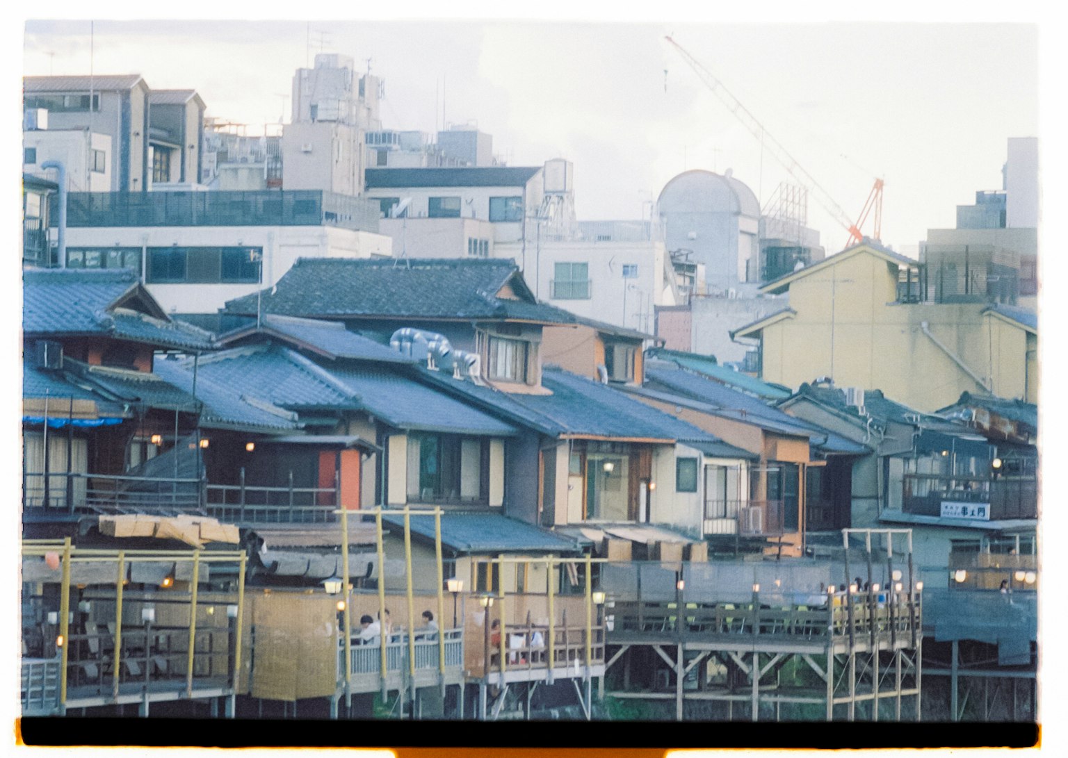 Maisons japonaises traditionnelles alignées près de l'eau avec des bâtiments modernes en arrière-plan