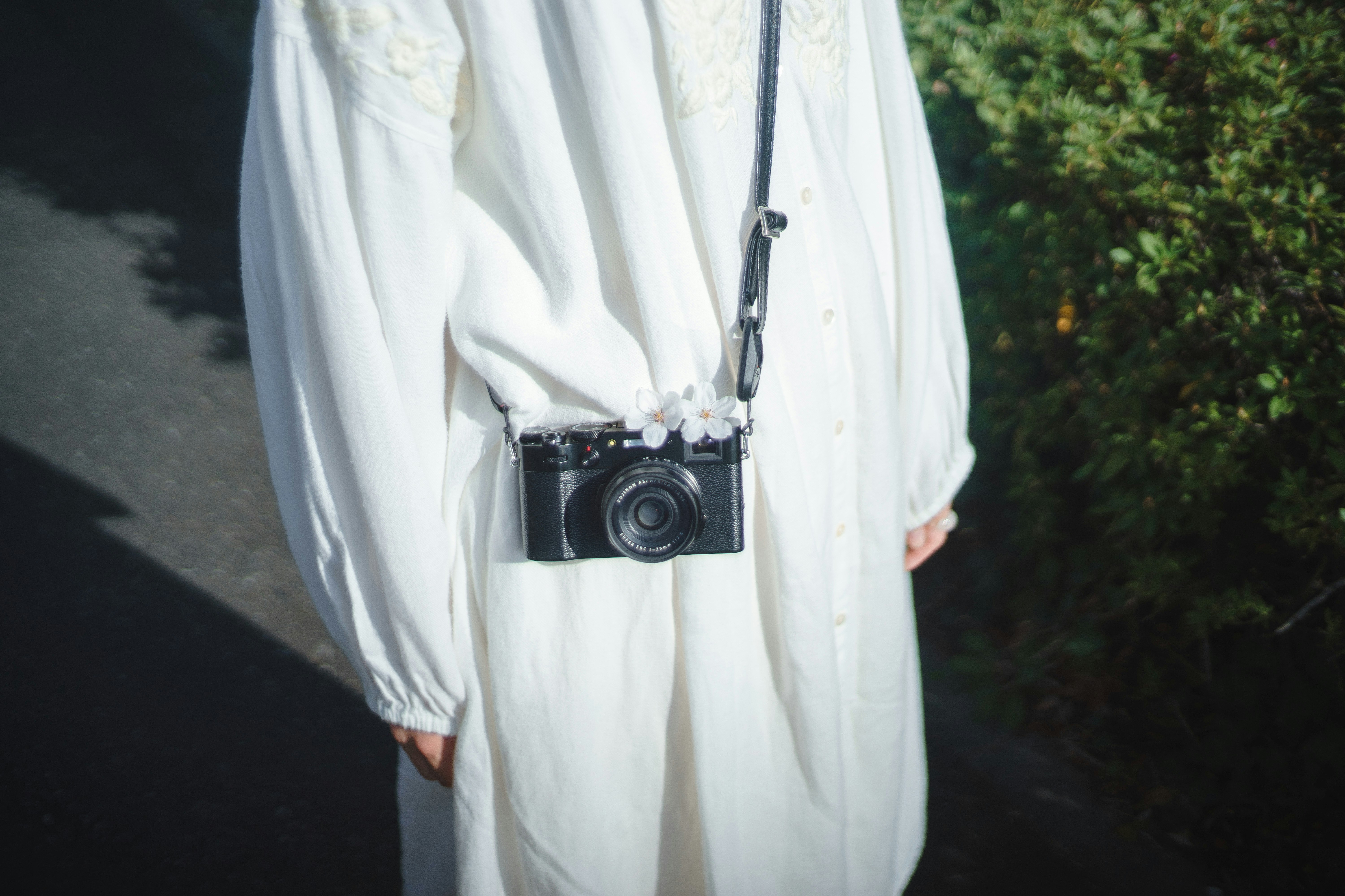 Une personne en tenue blanche portant un appareil photo en marchant sur un chemin