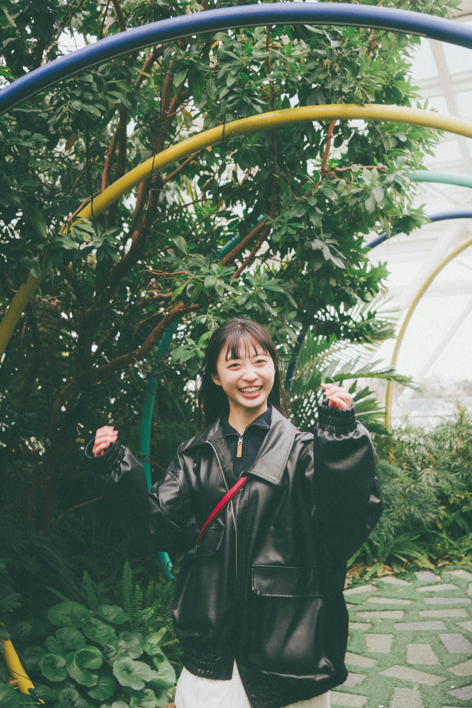 一名微笑的女性在郁郁蔥蔥的背景中擺姿勢